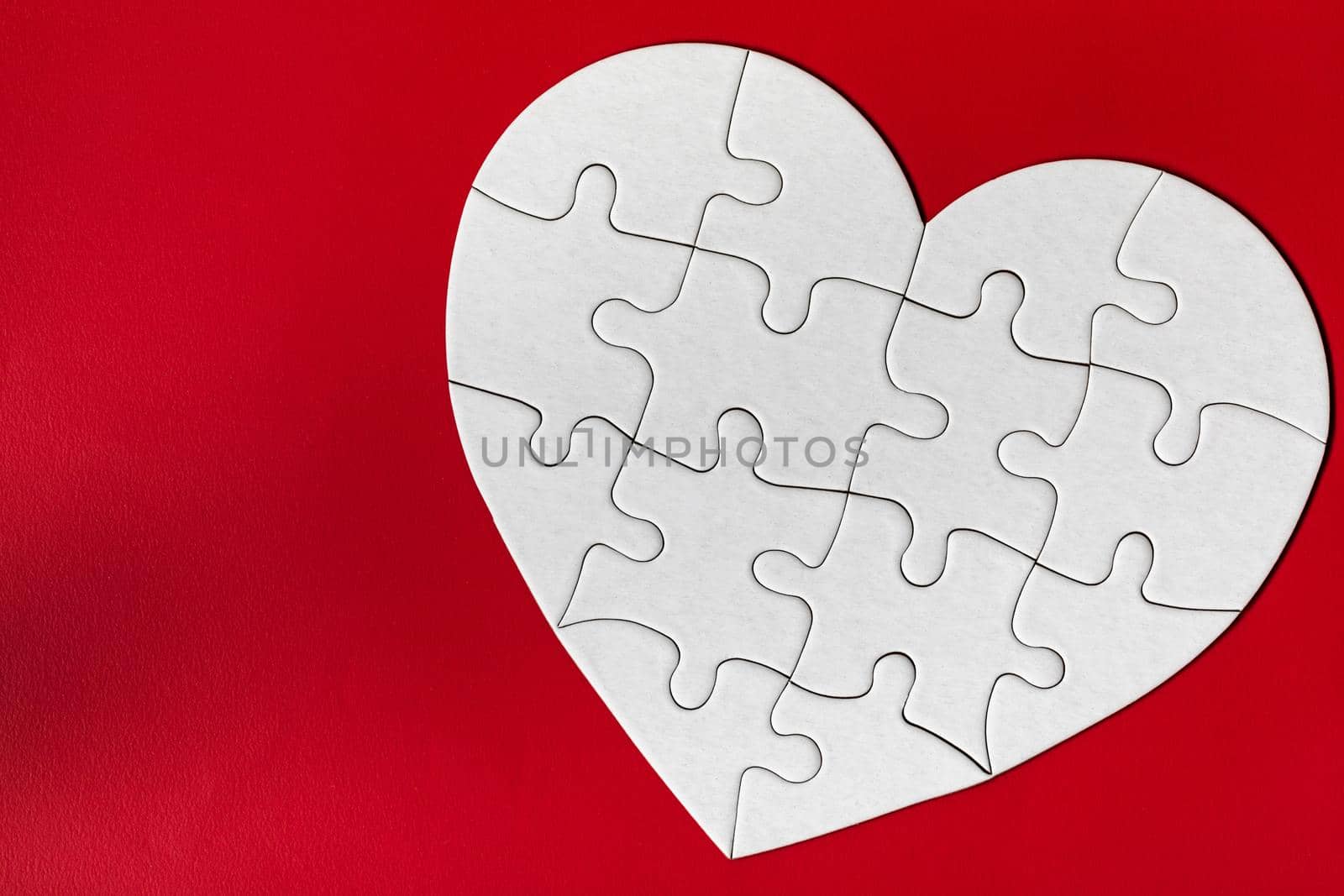 Heart-shaped jigsaw puzzle on color background. Puzzle heart on wooden background. A missing piece of the heart puzzle. Heart shape jigsaw puzzle. Puzzles in the shape of a heart. 