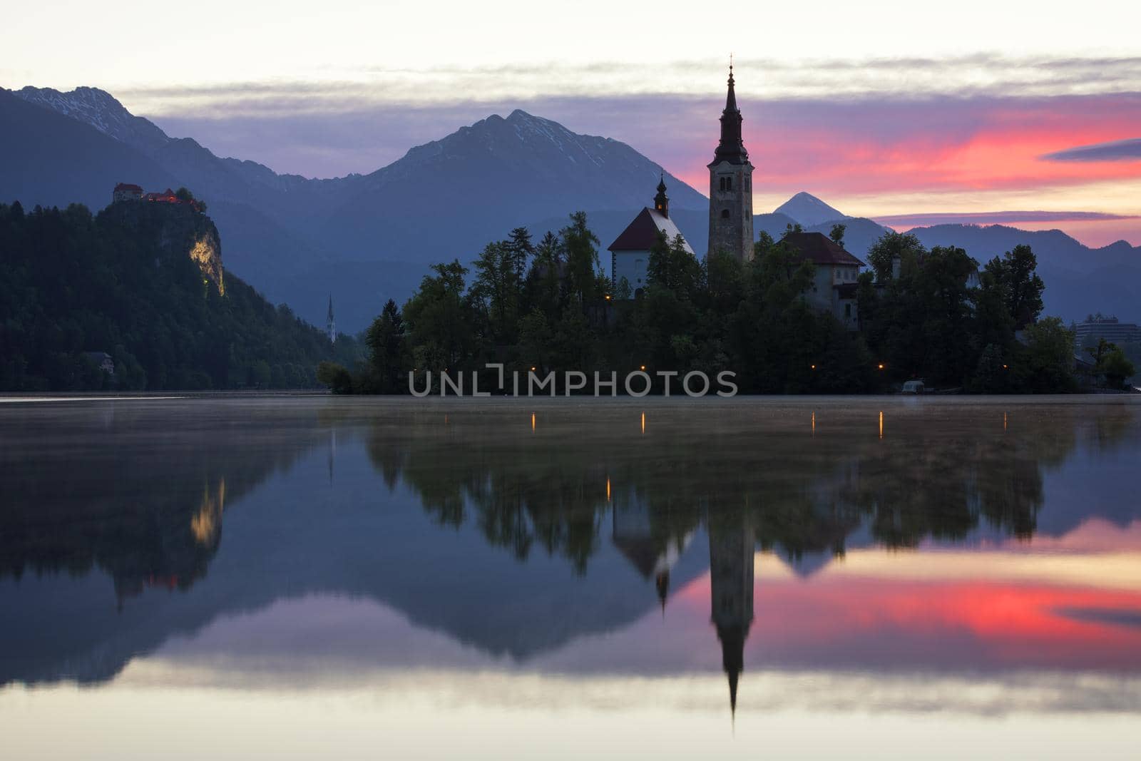 Dramatic sunrise on lake Bled, sunrise view on Bled lake, island, Pilgrimage Church of the Assumption of Maria and Castle with mountain range (Stol, Vrtaca, Begunjscica). Bled, Slovenia,
