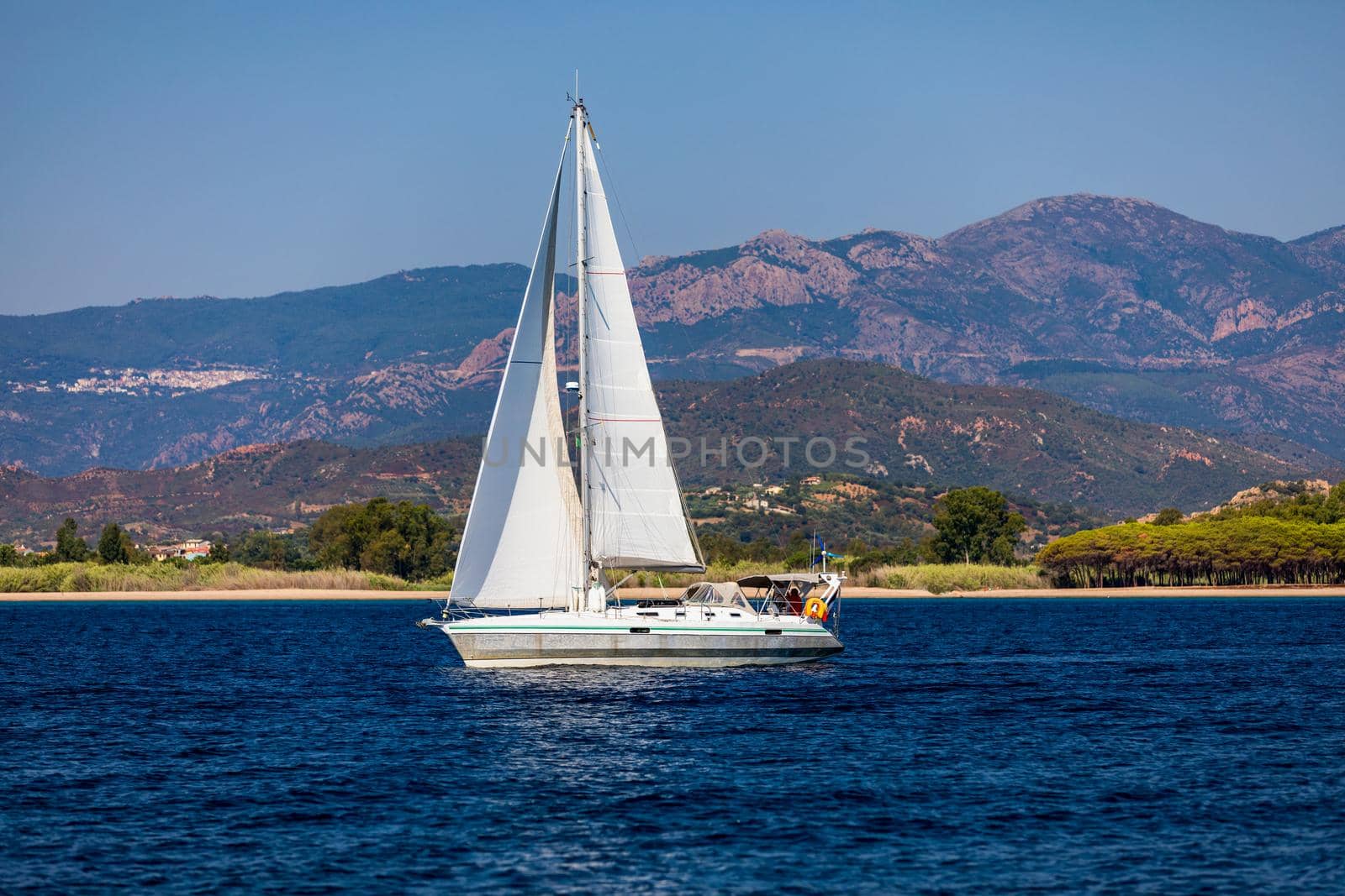 Aerial view of anchored sailing yacht in emerald sea. Aerial view of a boat. Outdoor water sports, yachting. Aerial view of anchoring yacht in open water. Ocean and sea travel and transportation