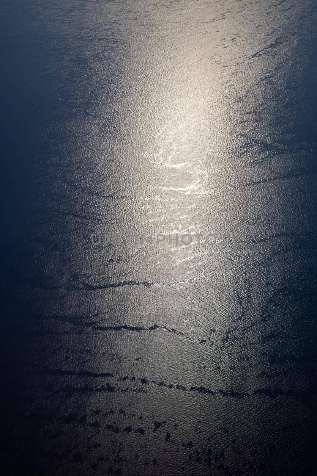 Sunlight twinkling and reflecting off sea water. Sparkles on water. Sun reflecting on the ocean surface, view from the plane, concept of travel. 