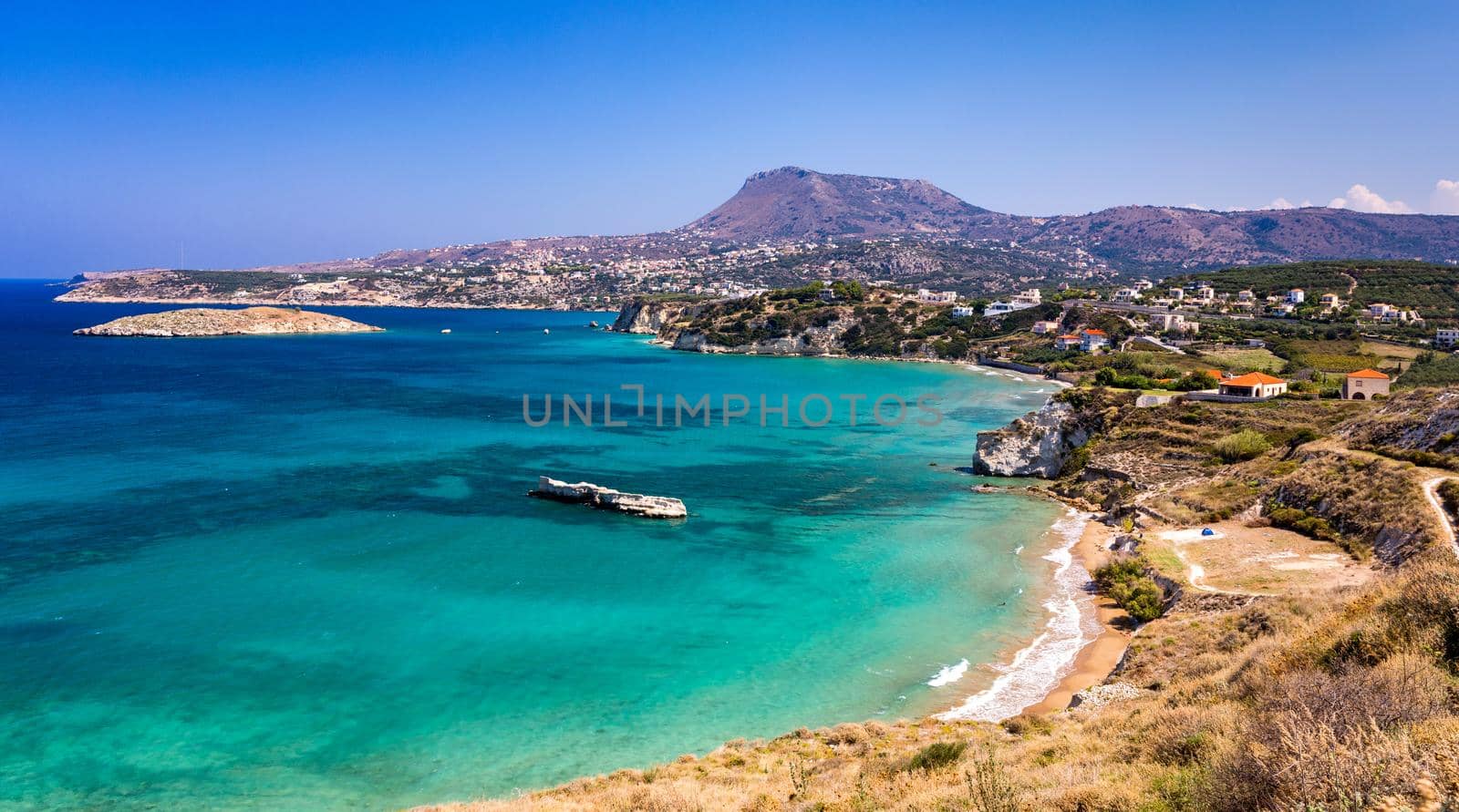 Greek holidays, beautiful Kalyves village with turquoise sea in Crete island, Greece. View of Kalyves beach, Crete. Tourists relaxing on the beach and views to the mountains, Kalyves, Crete, Greece