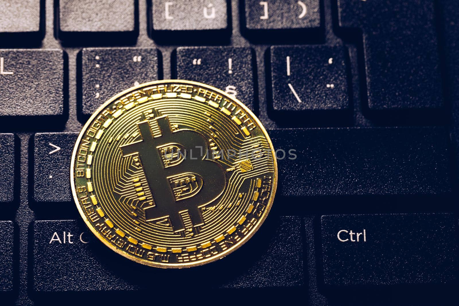 Bitcoin on compuer keyboard in background, symbol of electronic virtual money and mining cryptocurrency concept. Coin crypto currency bitcoin lies on the keyboard. Bitcoin on keyboard.