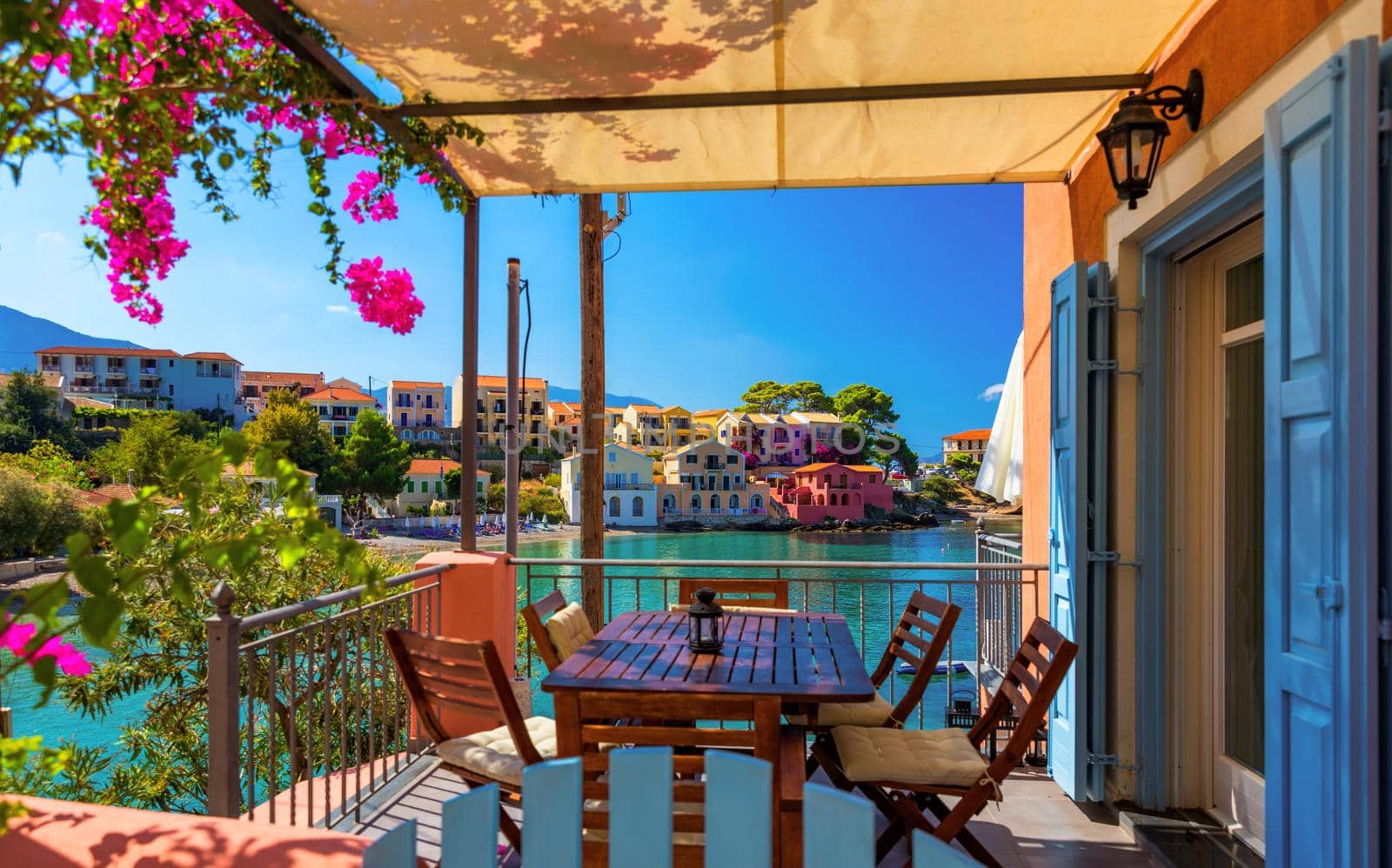 Traditional street with greek houses with flowers in Assos, Kefalonia island. Traditional colorful greek houses in Assos village. Blooming fuchsia plant flowers. Kefalonia island, Greece
