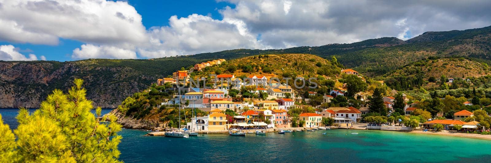 Assos village in Kefalonia, Greece. Turquoise colored bay in Mediterranean sea with beautiful colorful houses in Assos village in Kefalonia, Greece, Ionian island, Cephalonia, Assos village.