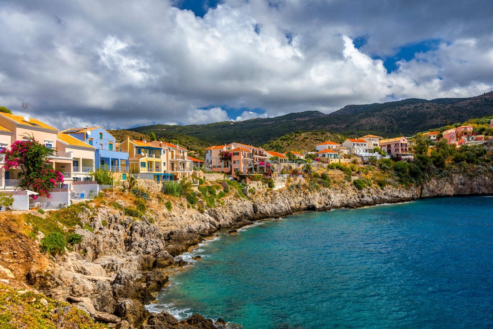 Assos village in Kefalonia, Greece. Turquoise colored bay in Mediterranean sea with beautiful colorful houses in Assos village in Kefalonia, Greece, Ionian island, Cephalonia, Assos village.