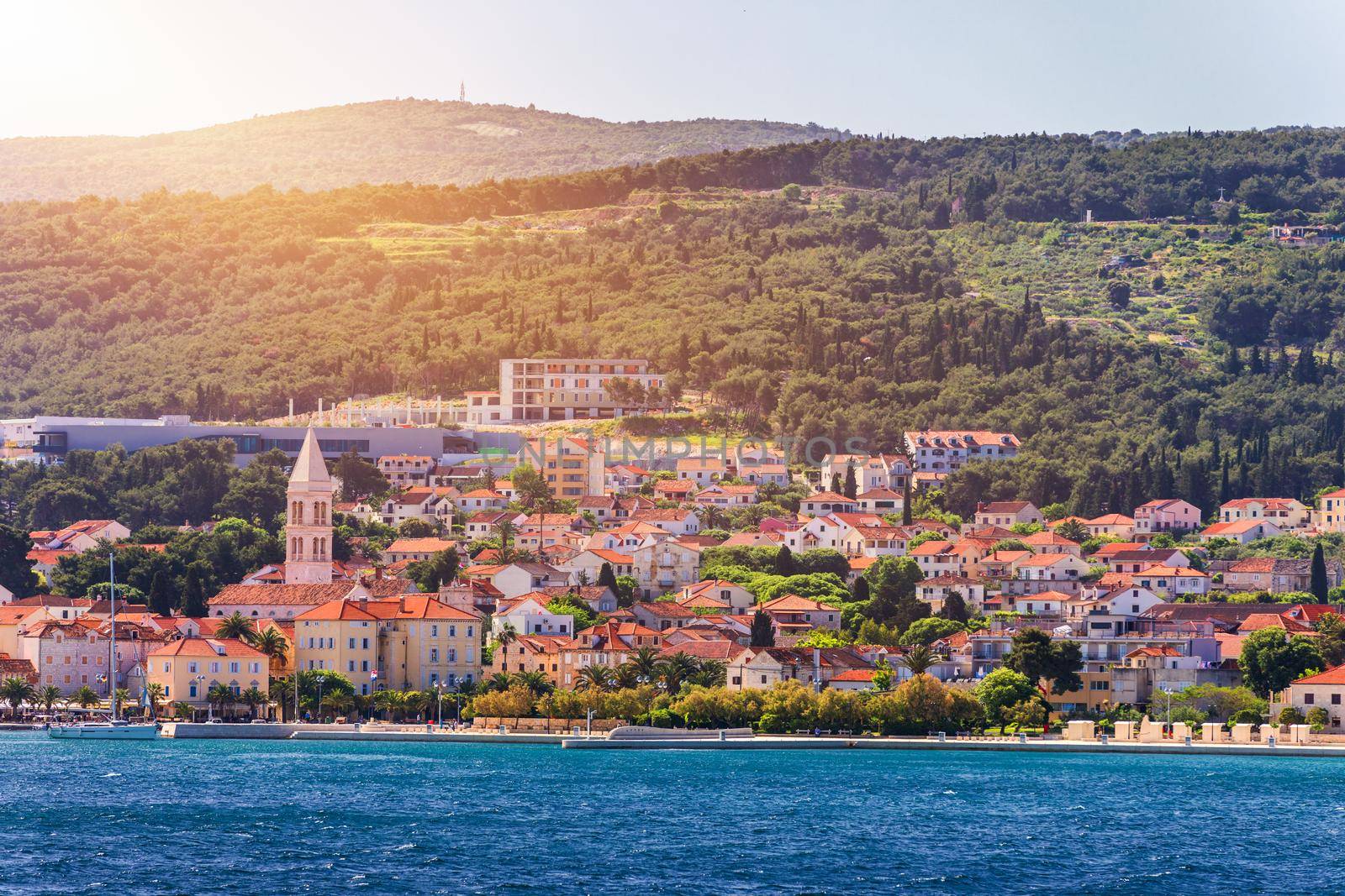 Supetar city in Brac island, Croatia. View from the sea. Picturesque scenic view on Supetar on Brac island, Croatia. Panoramic view on harbor of town Supetar from the side of sea. Brac, Croatia.