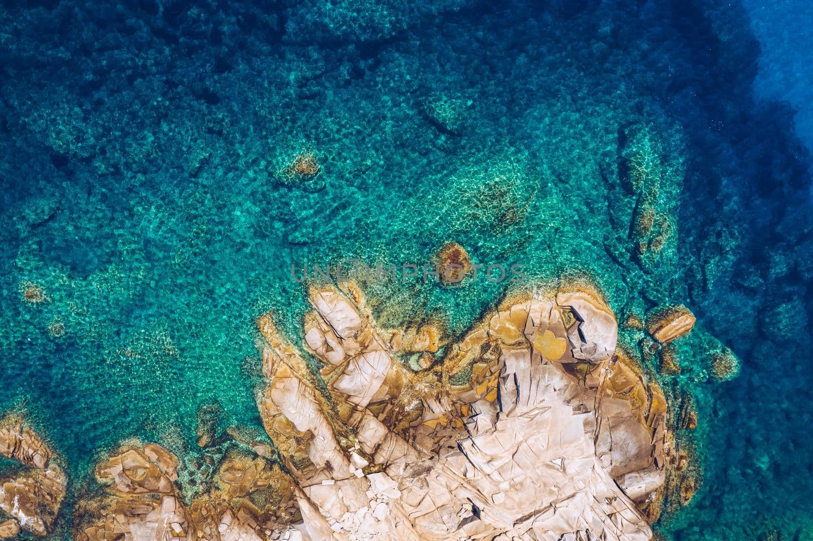 Aerial photo over granite rocky coastline Mediterranean crystal clear blue sea water. Aerial photo of ocean waves hitting rocky coastline of beautiful paradise dream tropical beach. Sardinia, Italy.
