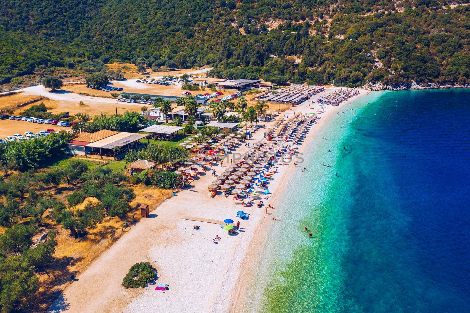 Concept of summer vacation. View from above, stunning aerial view of an amazing beach with beach umbrellas and turquoise clear water. Top view on a sun lounger under an umbrella on the sandy beach