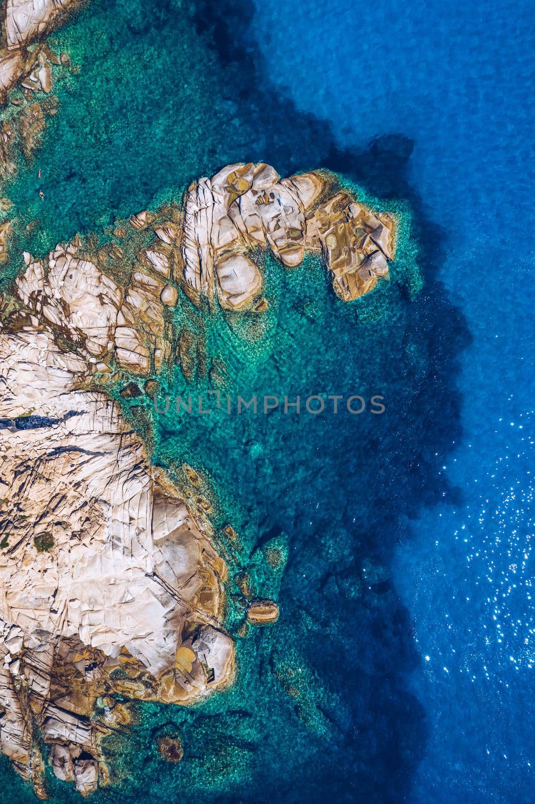 Aerial photo over granite rocky coastline Mediterranean crystal clear blue sea water. Aerial photo of ocean waves hitting rocky coastline of beautiful paradise dream tropical beach. Sardinia, Italy.