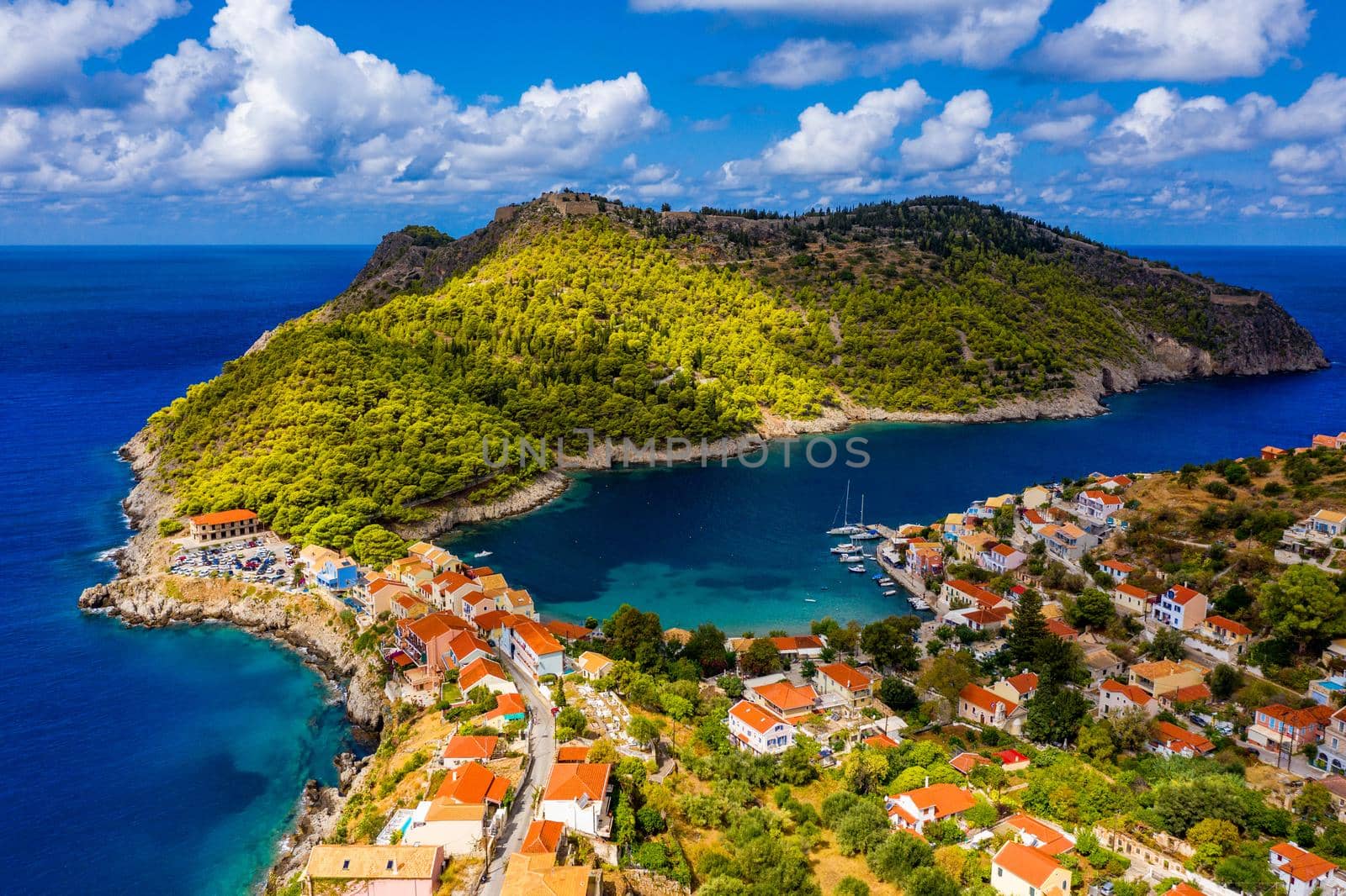 Turquoise colored bay in Mediterranean sea with beautiful colorful houses in Assos village in Kefalonia, Greece. Town of Assos with colorful houses on the mediterranean sea, Greece. 
