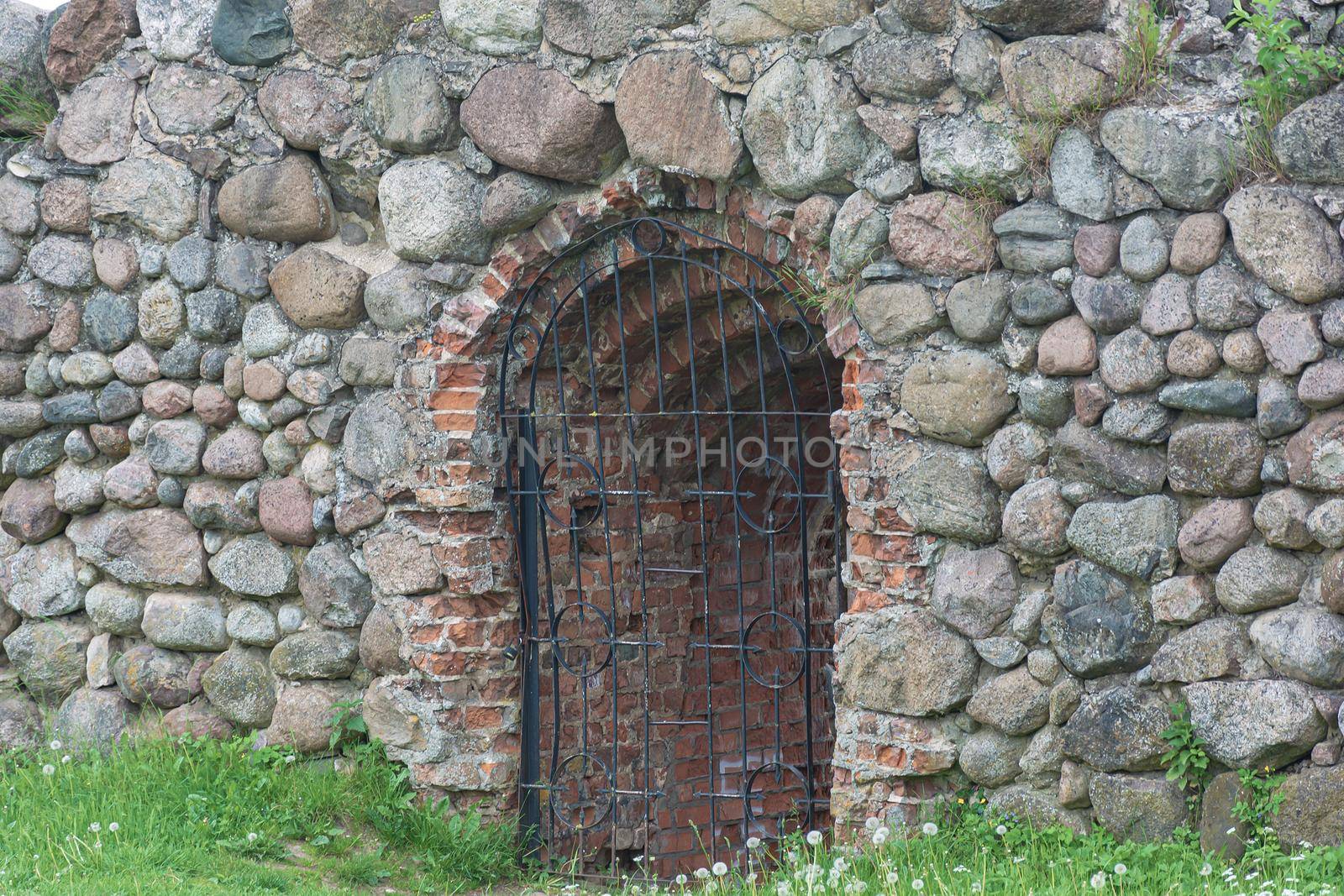 opening in the stone wall is closed with a latticework. Stock photography