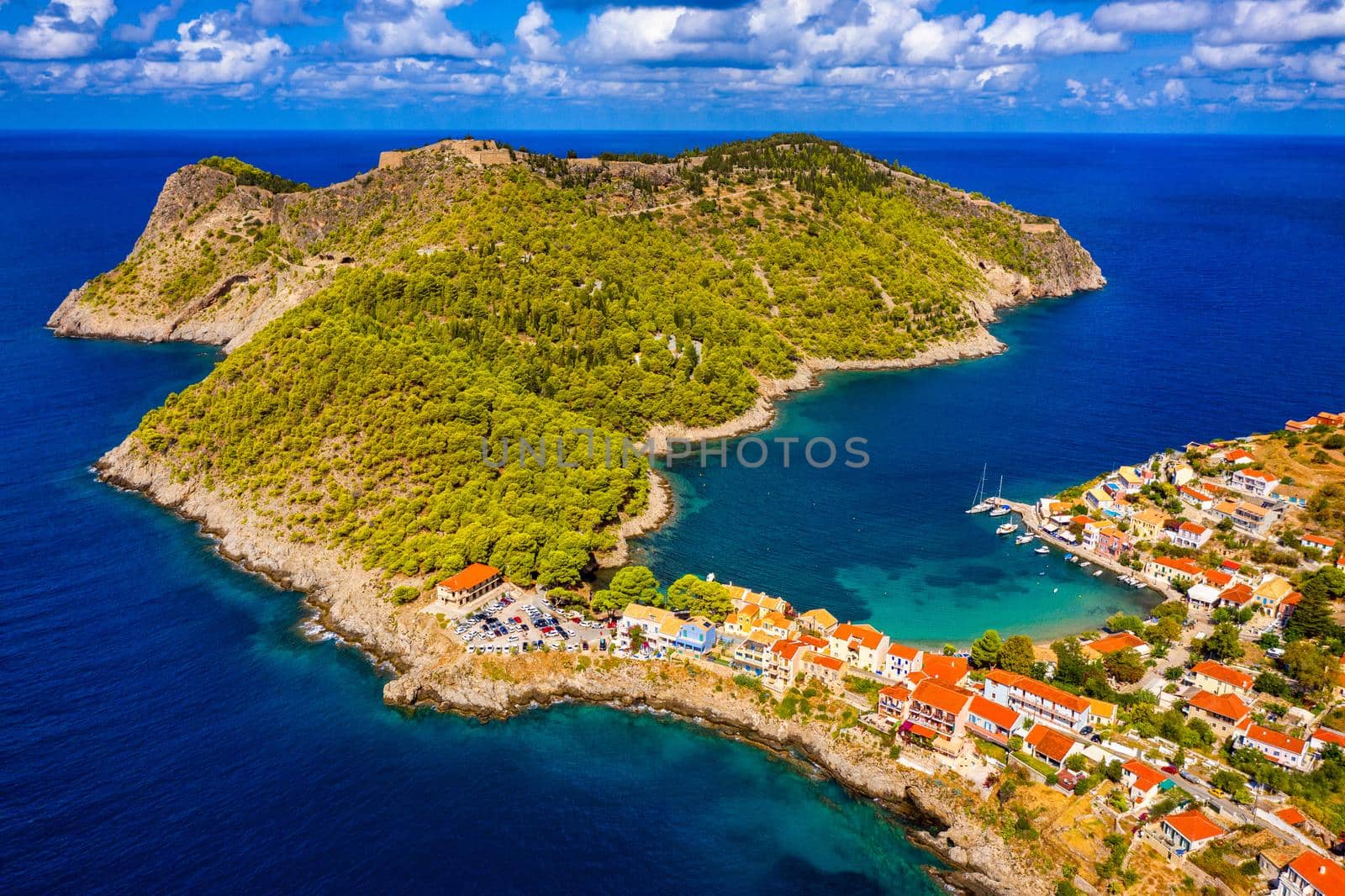 Turquoise colored bay in Mediterranean sea with beautiful colorful houses in Assos village in Kefalonia, Greece. Town of Assos with colorful houses on the mediterranean sea, Greece. 