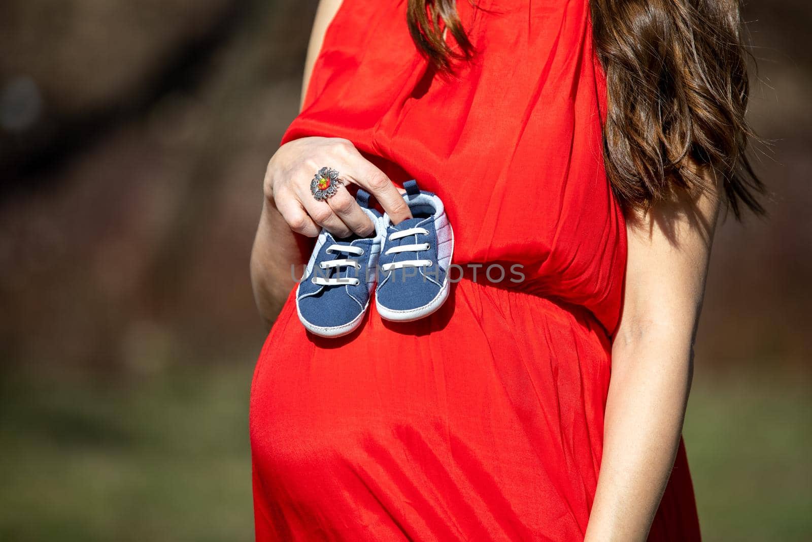 Young couple waiting for baby. Expecting parents with little baby boy shoes. Concept of Parents-To-Be. Shoes and sneakers of parents and expected baby. Mom, dad and the future baby Shoes.