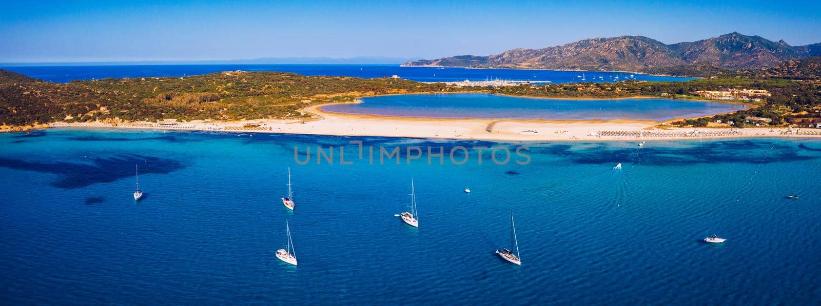 Aerial view of anchored sailing yacht in emerald sea. Aerial view of a boat. Outdoor water sports, yachting. Aerial view of anchoring yacht in open water. Ocean and sea travel and transportation