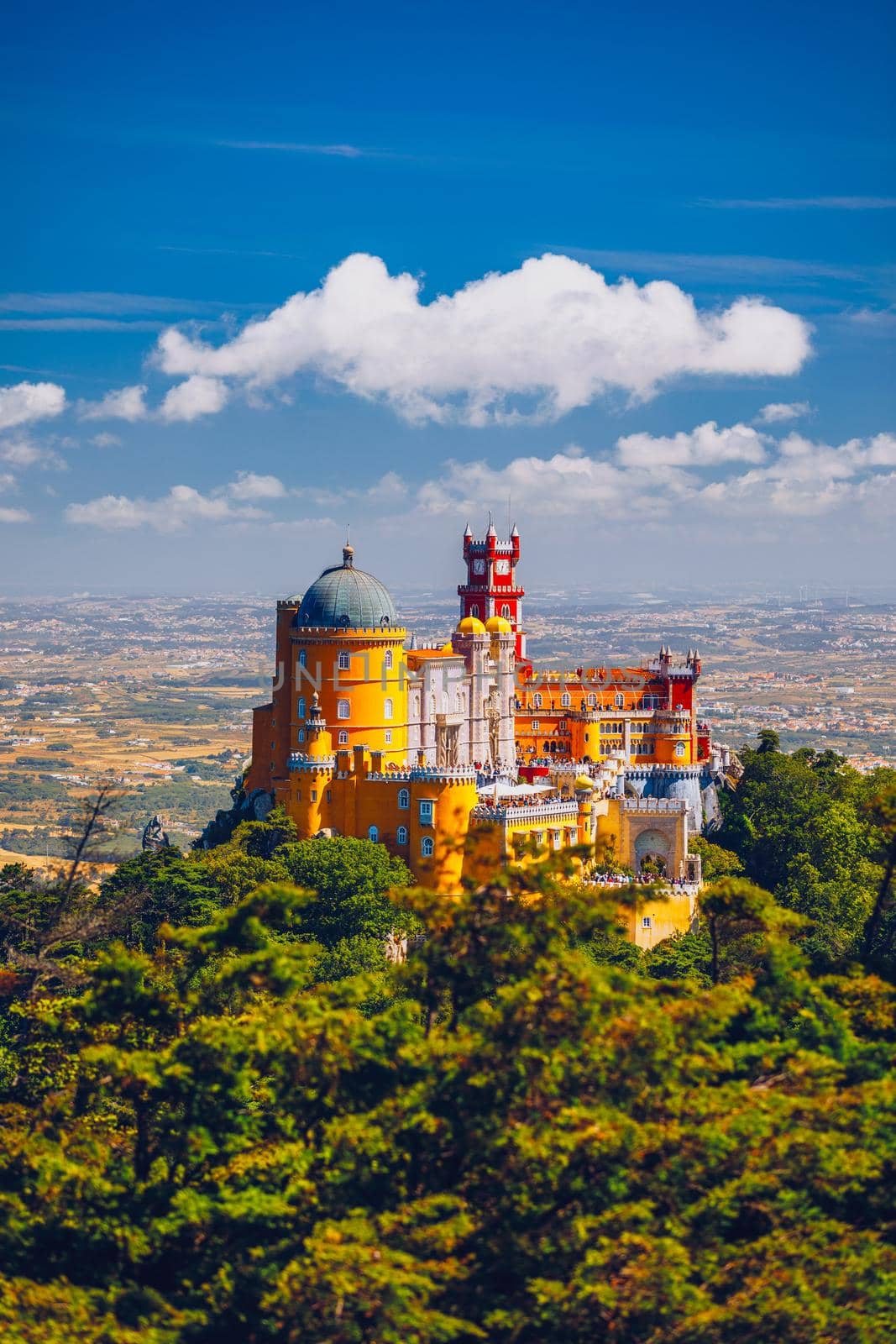 Famous historic Pena palace part of cultural site of Sintra against sunset sky in Portugal. Panoramic View Of Pena Palace, Sintra, Portugal. Pena National Palace at sunset, Sintra, Portugal. 