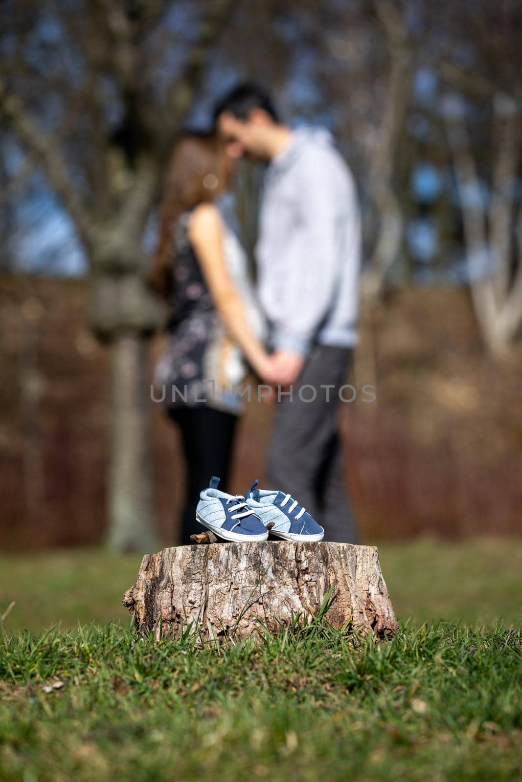 Young couple waiting for baby. Expecting parents with little baby boy shoes. Concept of Parents-To-Be. Shoes and sneakers of parents and expected baby. Mom, dad and the future baby Shoes.