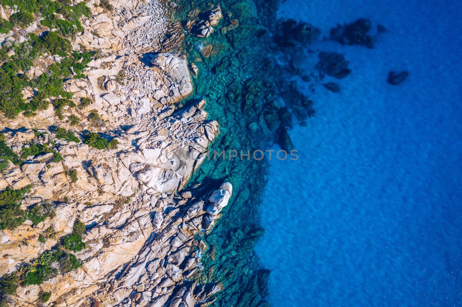 Aerial photo over granite rocky coastline Mediterranean crystal clear blue sea water. Aerial photo of ocean waves hitting rocky coastline of beautiful paradise dream tropical beach. Sardinia, Italy.