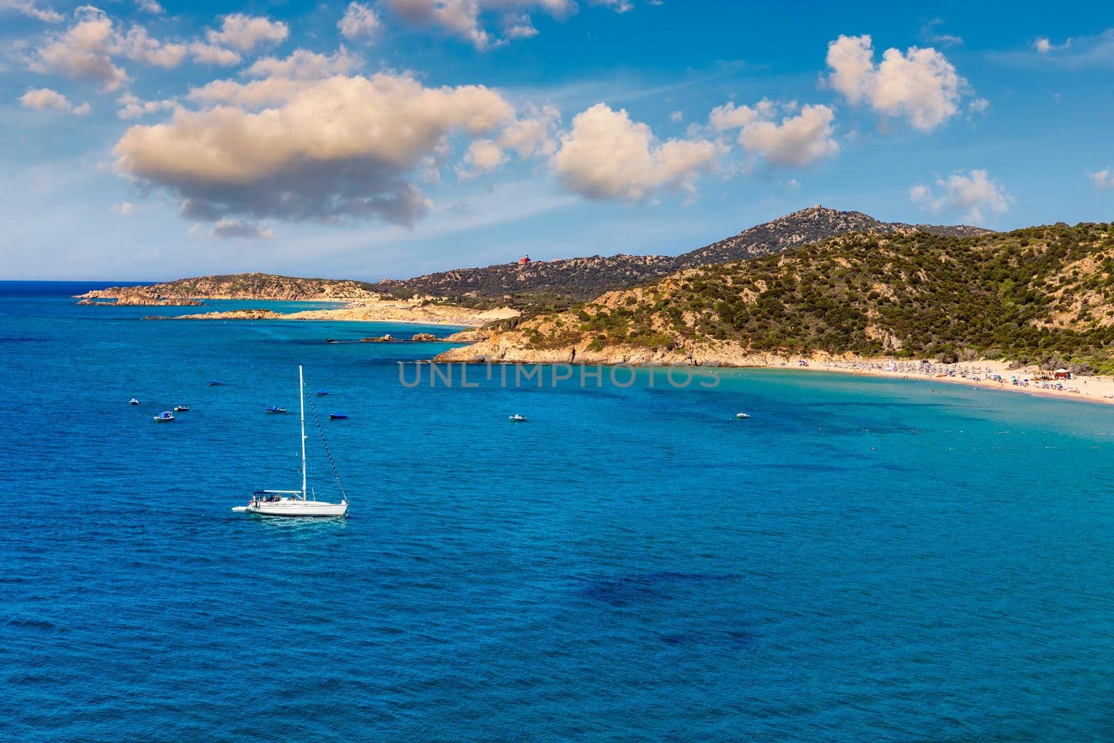 Yacht anchoring in crystal clear turquoise water in front of the tropical island, alternative lifestyle, living on a boat. Aerial view of yacht at anchor on turquoise water, showing luxury, wealth.