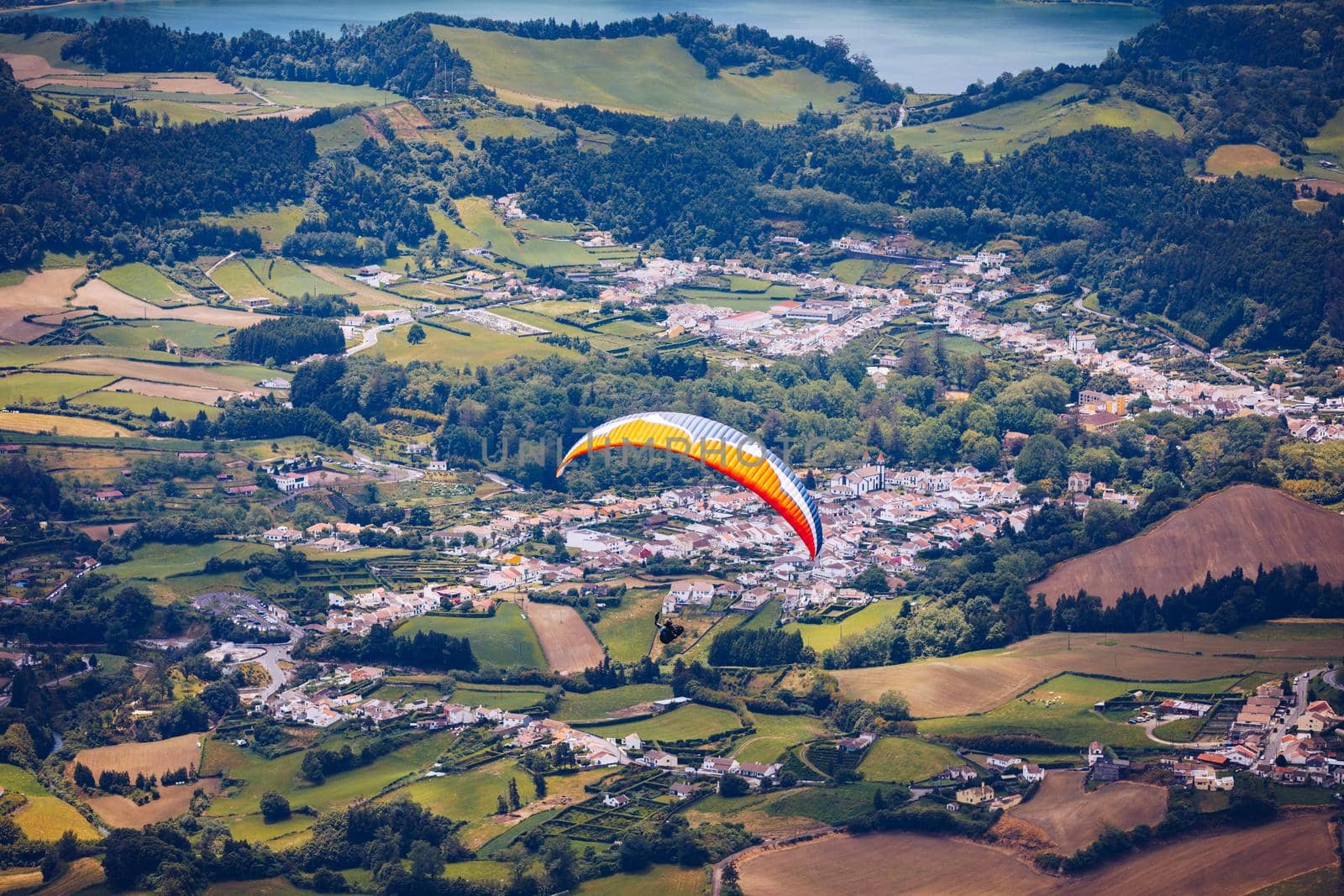 Paragliding in paradise landscape with volcano crater and lagoon in Azores. Paraglider above Lagoa das Furnas, Sao Miguel, Azores, Portugal, Europe