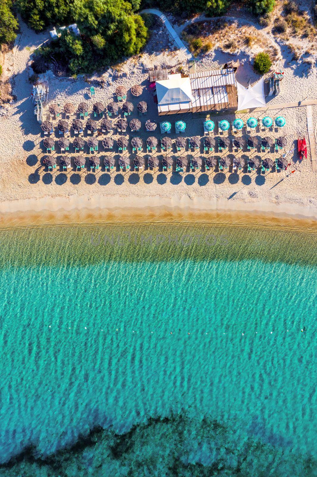 View from above, stunning aerial view of an amazing beach with beach umbrellas and turquoise clear water. Top view on sun loungers under umbrellas on the sandy beach. Concept of summer vacation. 