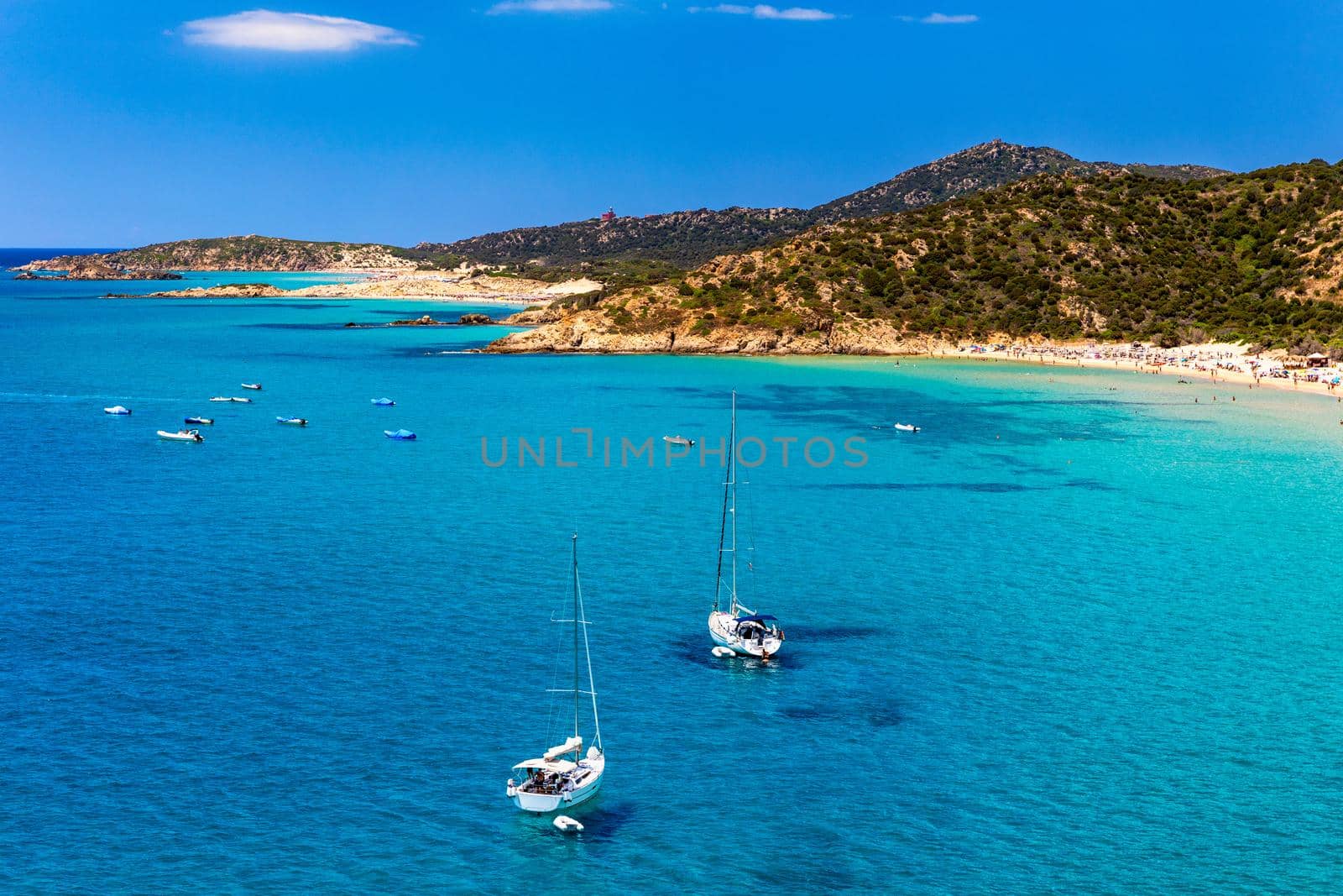 Yacht anchoring in crystal clear turquoise water in front of the tropical island, alternative lifestyle, living on a boat. Aerial view of yacht at anchor on turquoise water, showing luxury, wealth.
