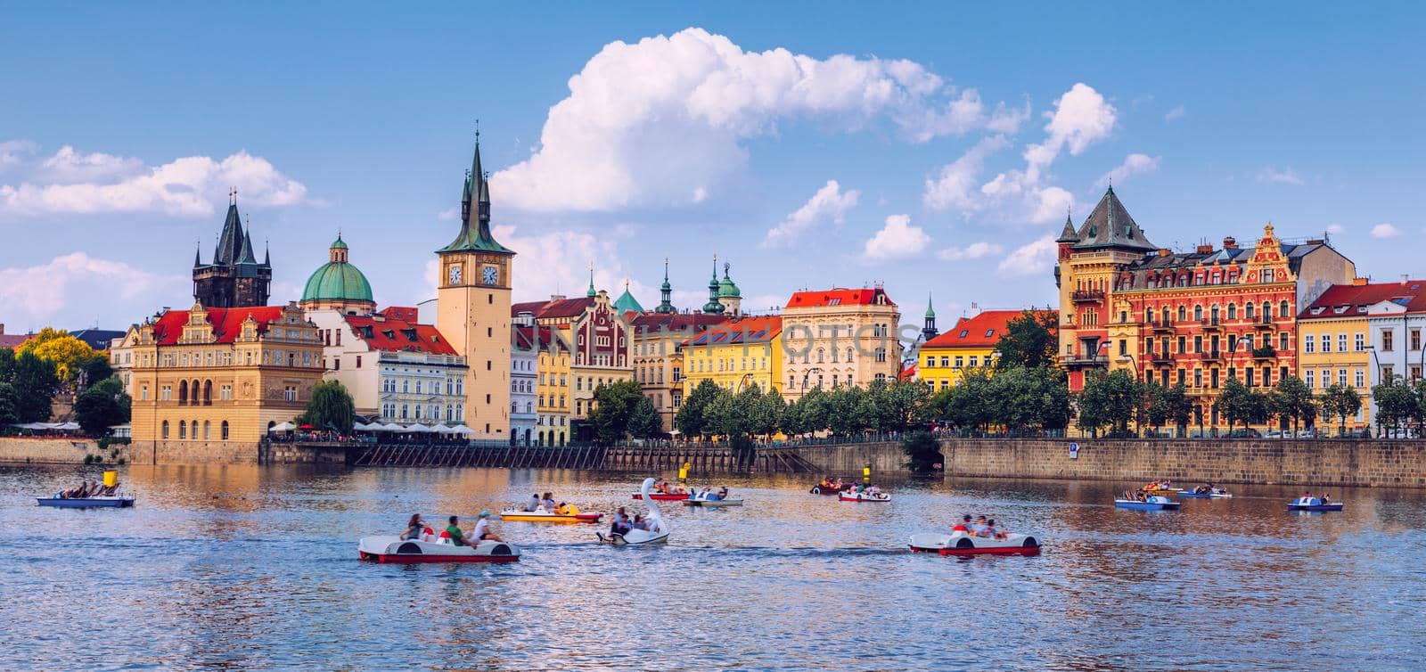 Scenic embankment in Prague city with paddle boats on Vltava river and Charles bridge; Historical center of Prague, buildings and landmarks of old town, Prague, Czech Republic