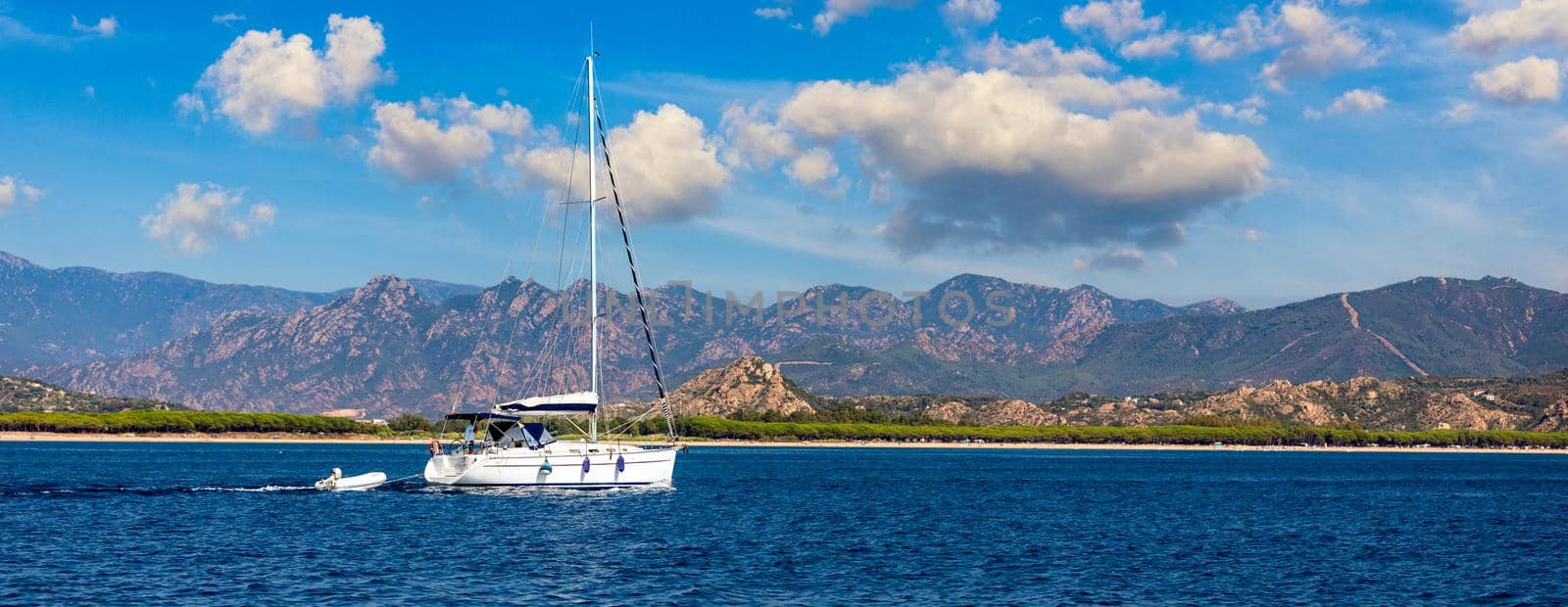 Aerial view of anchored sailing yacht in emerald sea. Aerial view of a boat. Outdoor water sports, yachting. Aerial view of anchoring yacht in open water. Ocean and sea travel and transportation