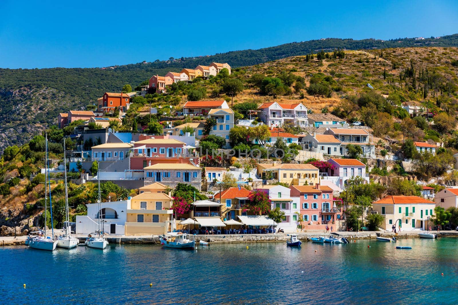Turquoise colored bay in Mediterranean sea with beautiful colorful houses in Assos village in Kefalonia, Greece. Town of Assos with colorful houses on the mediterranean sea, Greece. 