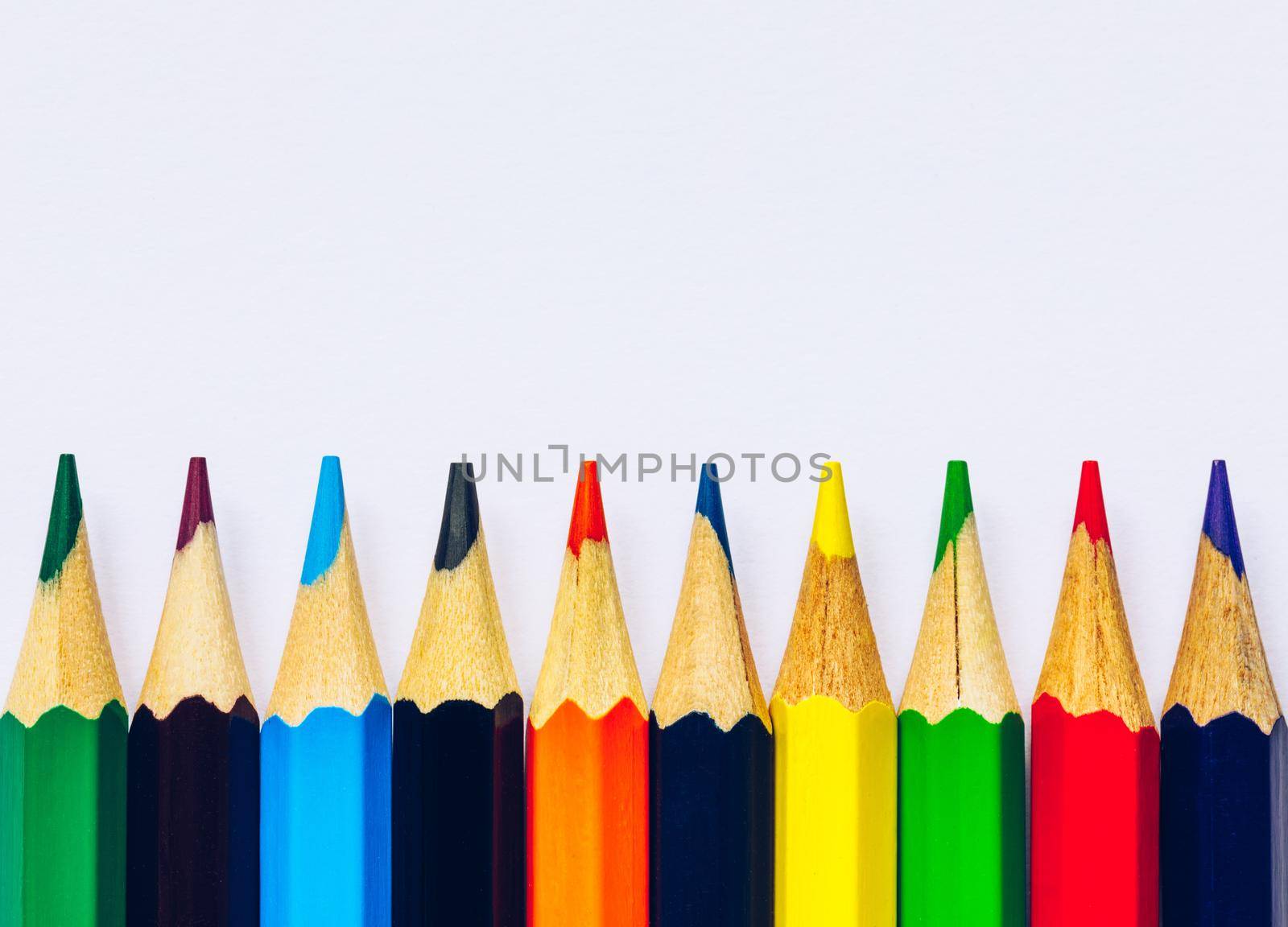 Color pencils isolated on white background. Close up of colored rainbow pencils for drawing, concept of preparing for school and discounts on stationery before the school year.