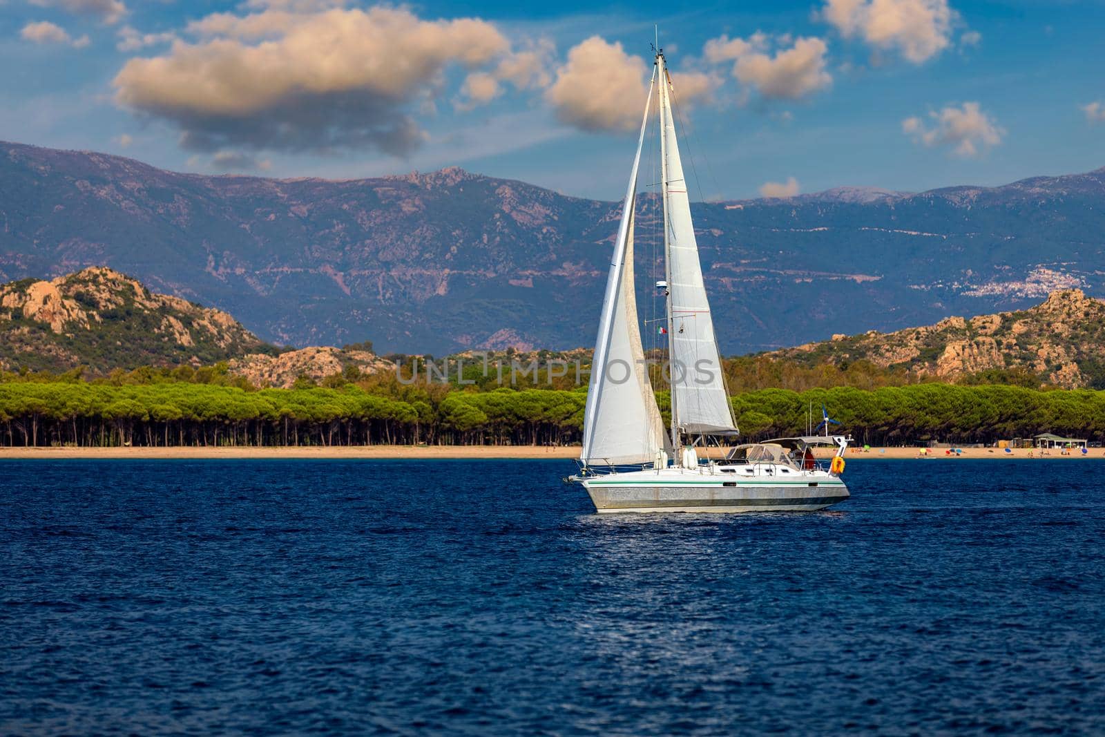 Yacht anchoring in crystal clear turquoise water in front of the tropical island, alternative lifestyle, living on a boat. Aerial view of yacht at anchor on turquoise water, showing luxury, wealth.