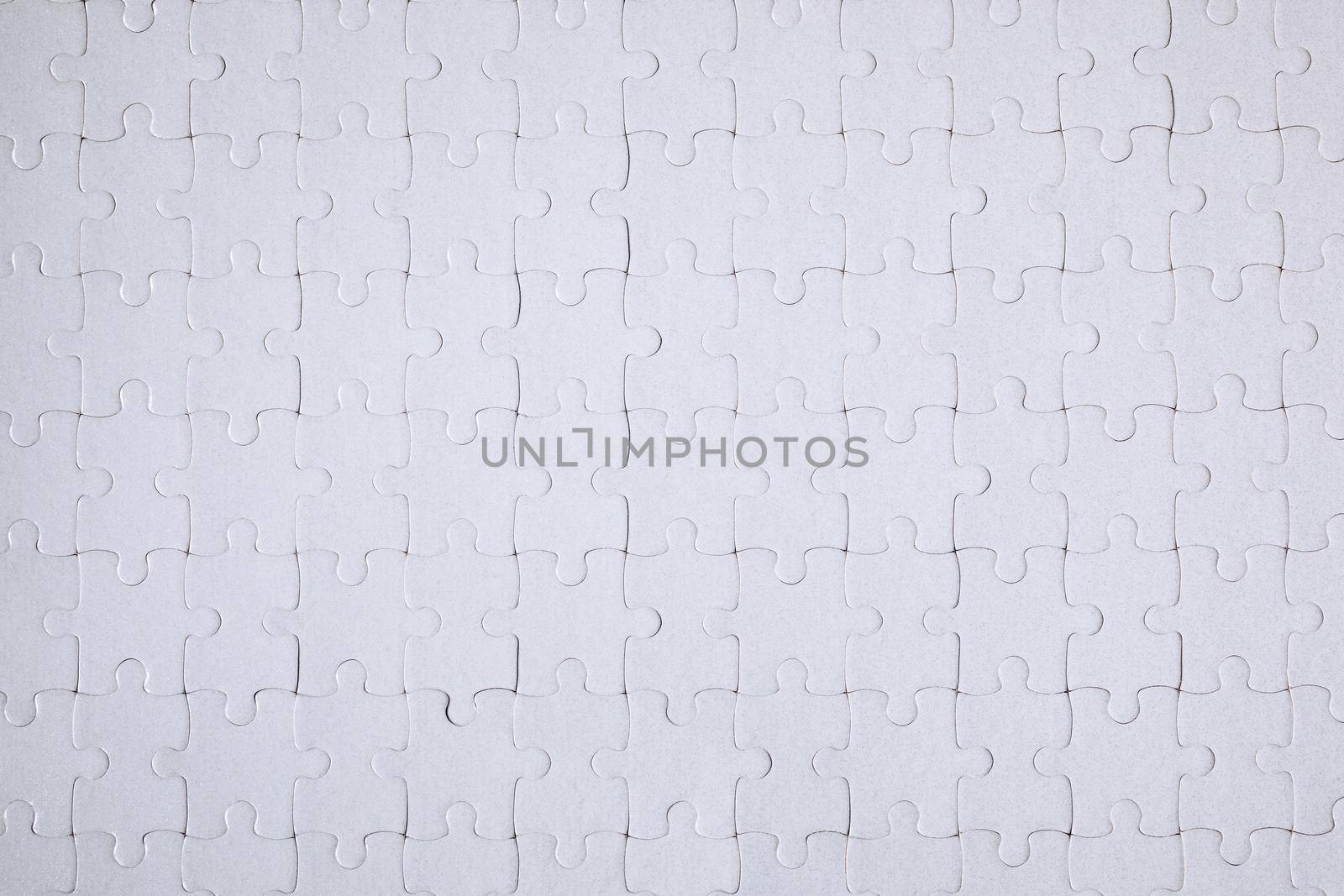 White jigsaw puzzle. White puzzle pieces on color background. Unfinished white jigsaw puzzle pieces on color background. 