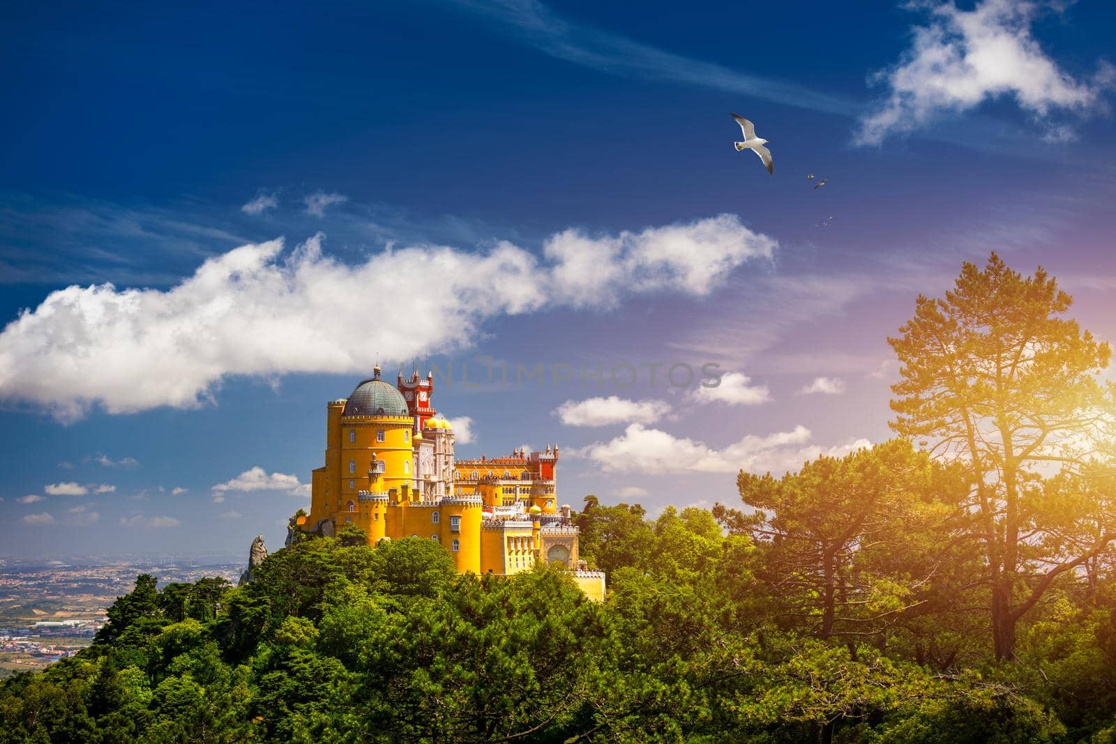 Famous historic Pena palace part of cultural site of Sintra against sunset sky in Portugal. Panoramic View Of Pena Palace, Sintra, Portugal. Pena National Palace at sunset, Sintra, Portugal. 