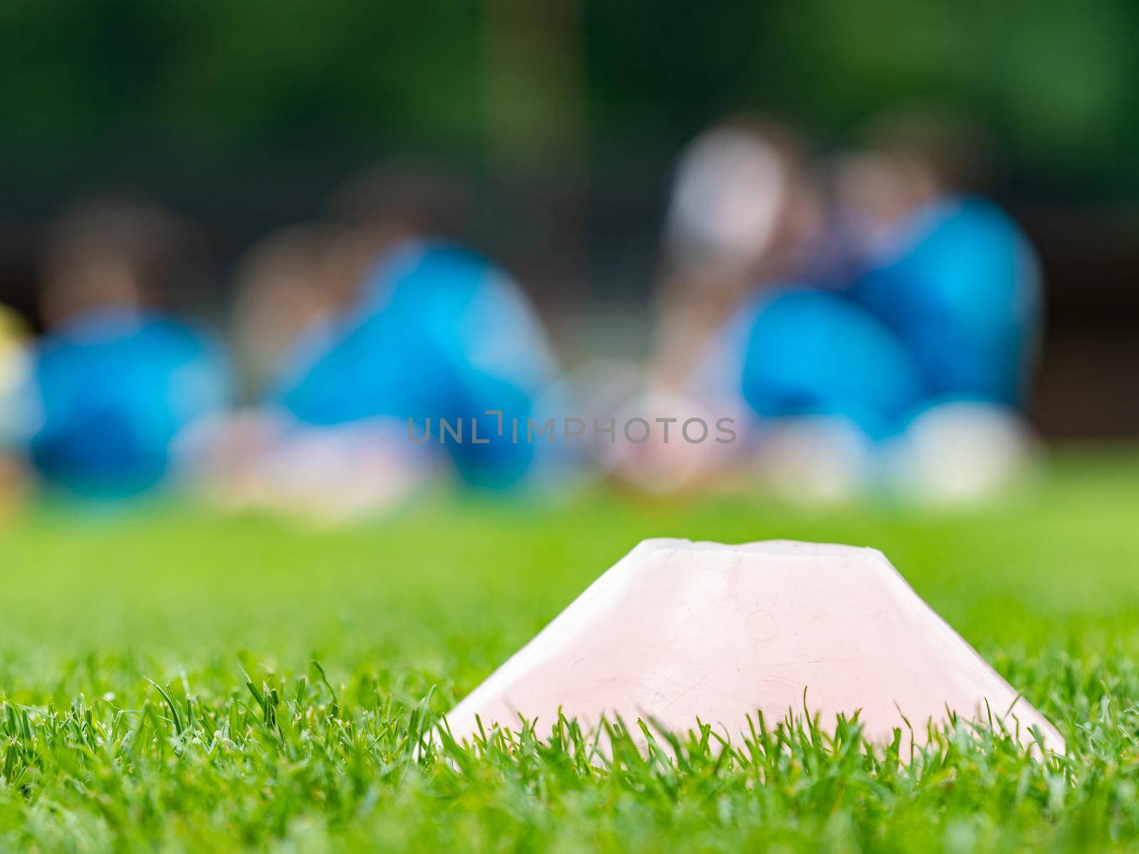 Sport plastic training marker on a grass training venue. Players running in a blurred background