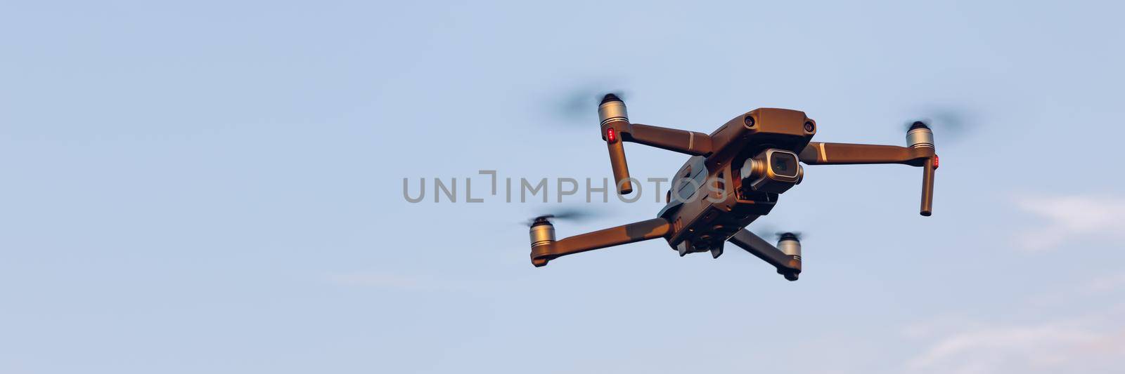 Drone flying over landscape. UAV drone copter flying with digital camera. Drone flying overhead in cloudy blue sky. Quad copter is flying over the  field.