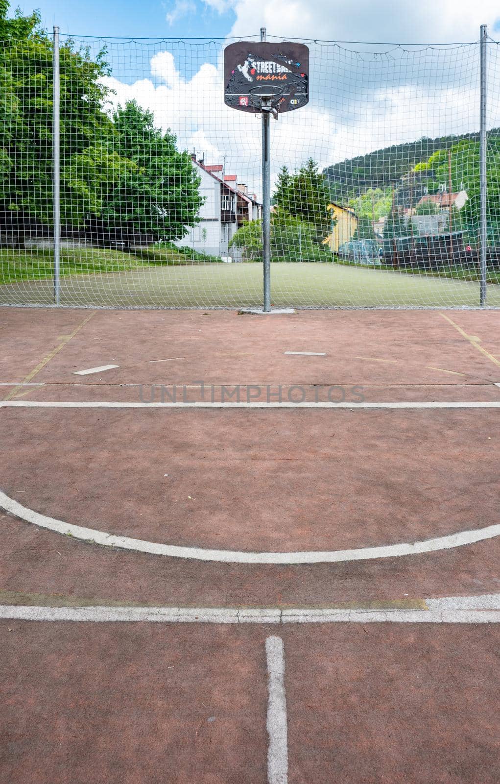 Basketball and a basket in an outdoor court with natural sun lightning.
