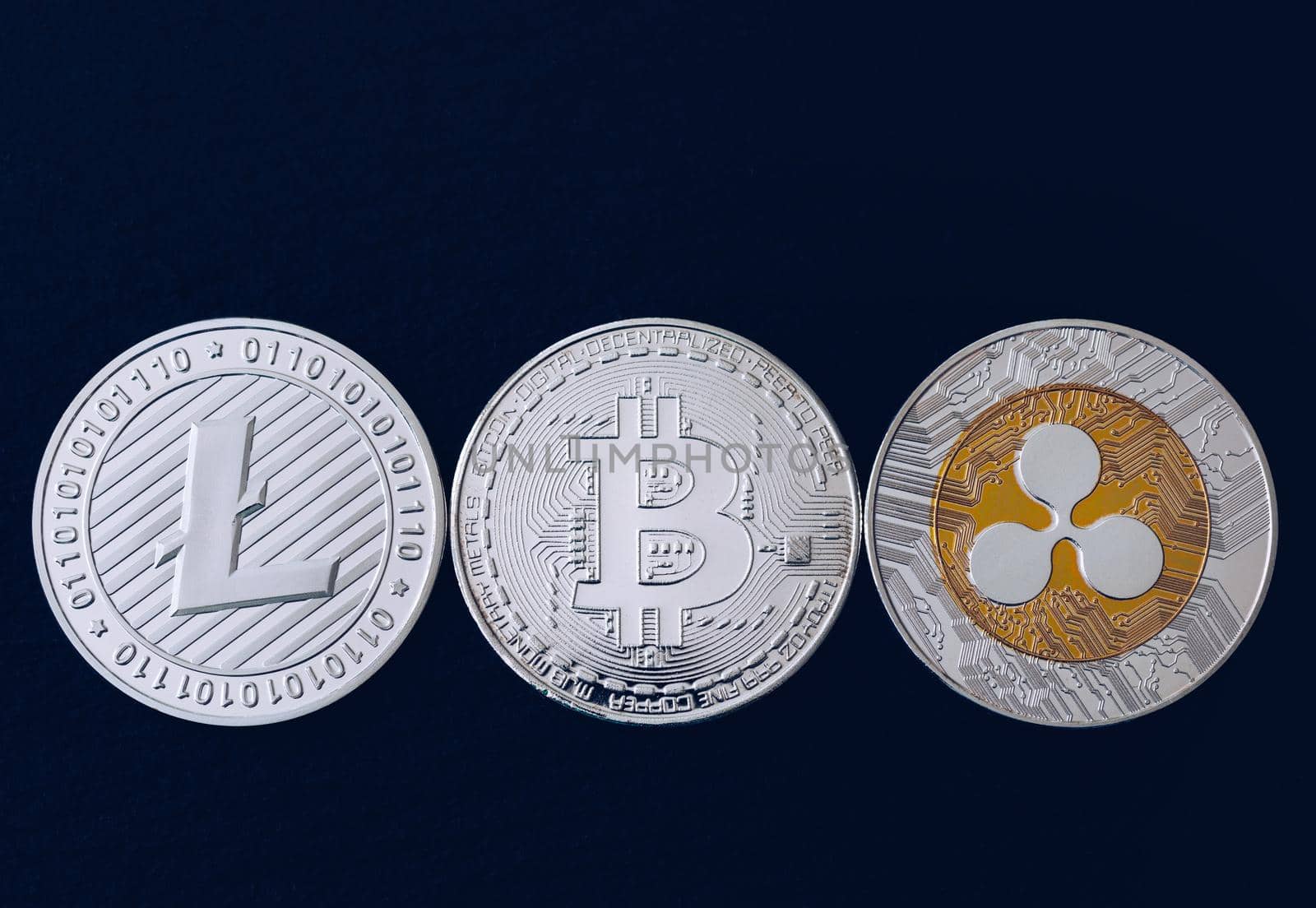 Bitcoin, litecoin and ripple coins currency finance money on graph chart background. Bitcoin as most important cryptocurrency concept. Stack of cryptocurrencies with a golden bitcoin in the middle.