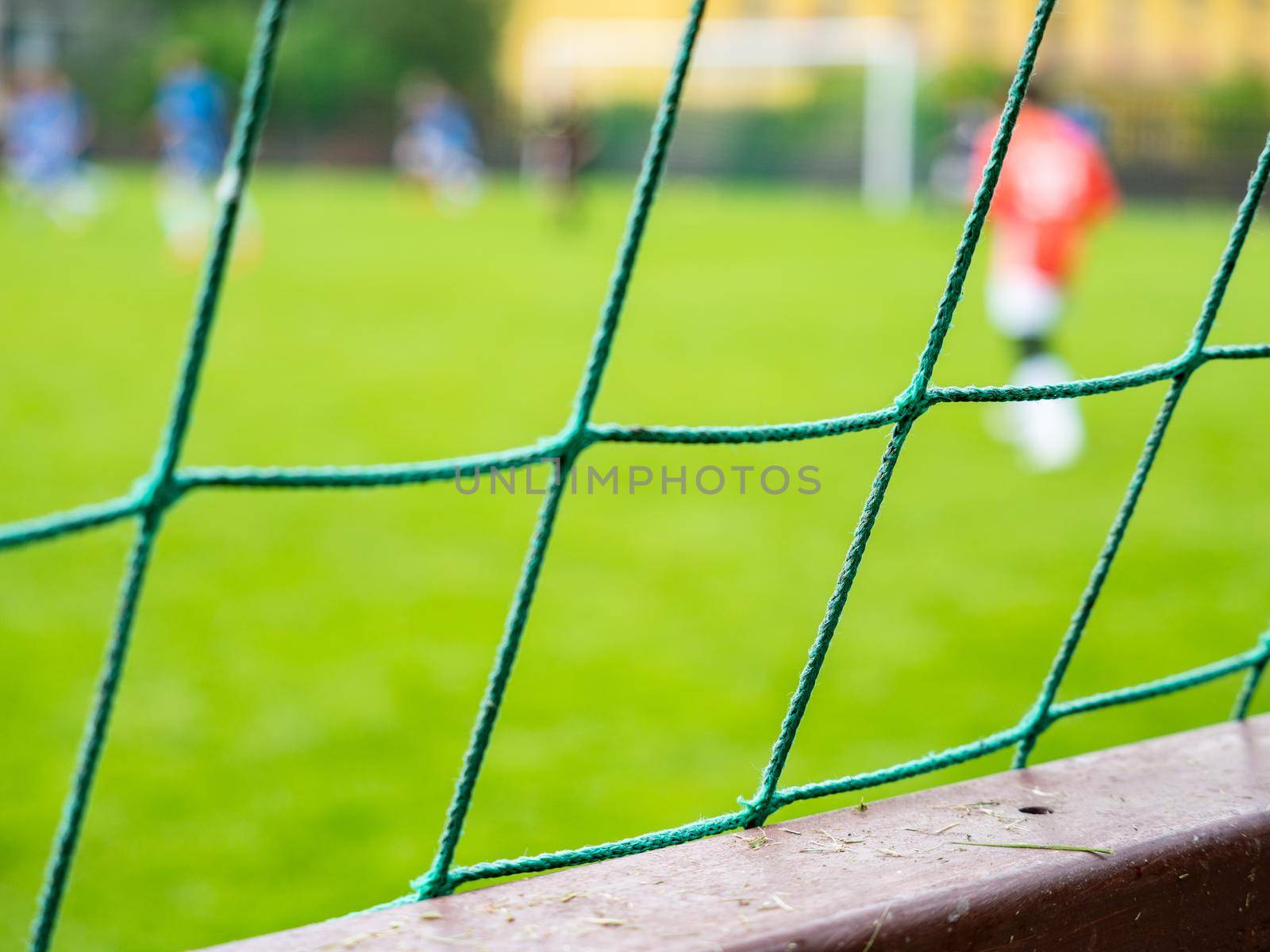 Soccer game behind the barrier or fence, the goal keeper in red wearing