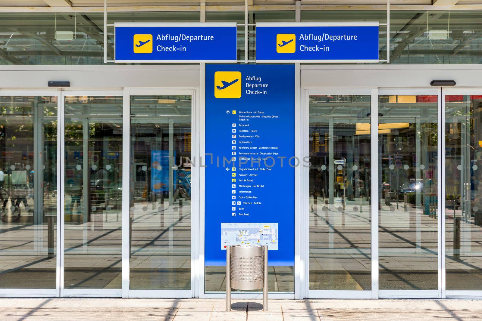 Airport terminal building gate entrance and automatic glass door with info text in german and english. Modern airport glass wall aisle window and door. Terminal entrance, automatic glass doors.