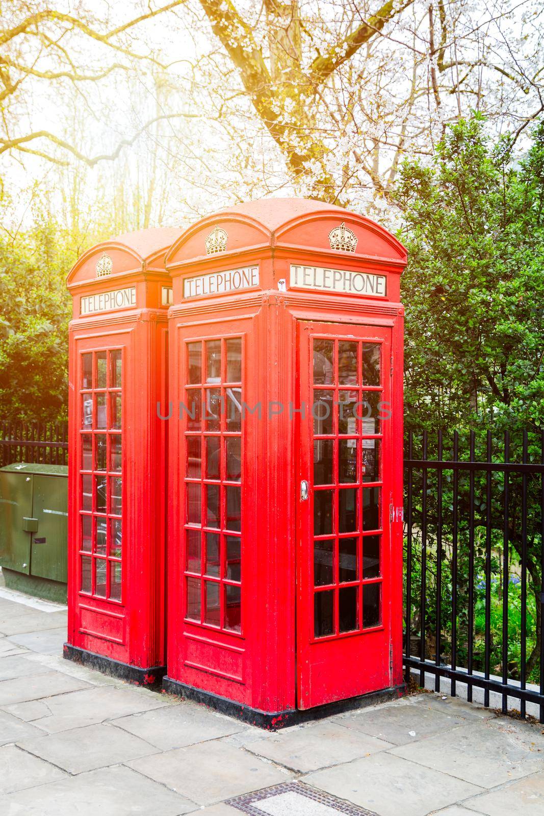 Red telephone box in street with historical architecture in London.