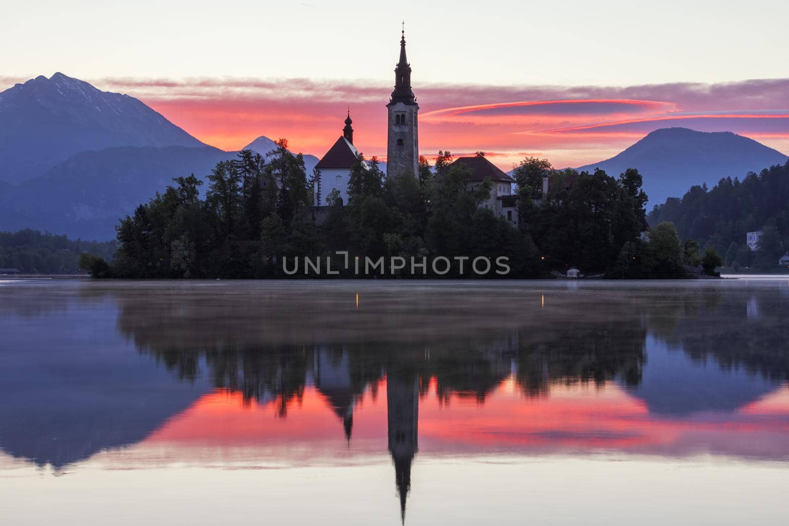 Dramatic sunrise on lake Bled, sunrise view on Bled lake, island, Pilgrimage Church of the Assumption of Maria and Castle with mountain range (Stol, Vrtaca, Begunjscica). Bled, Slovenia,