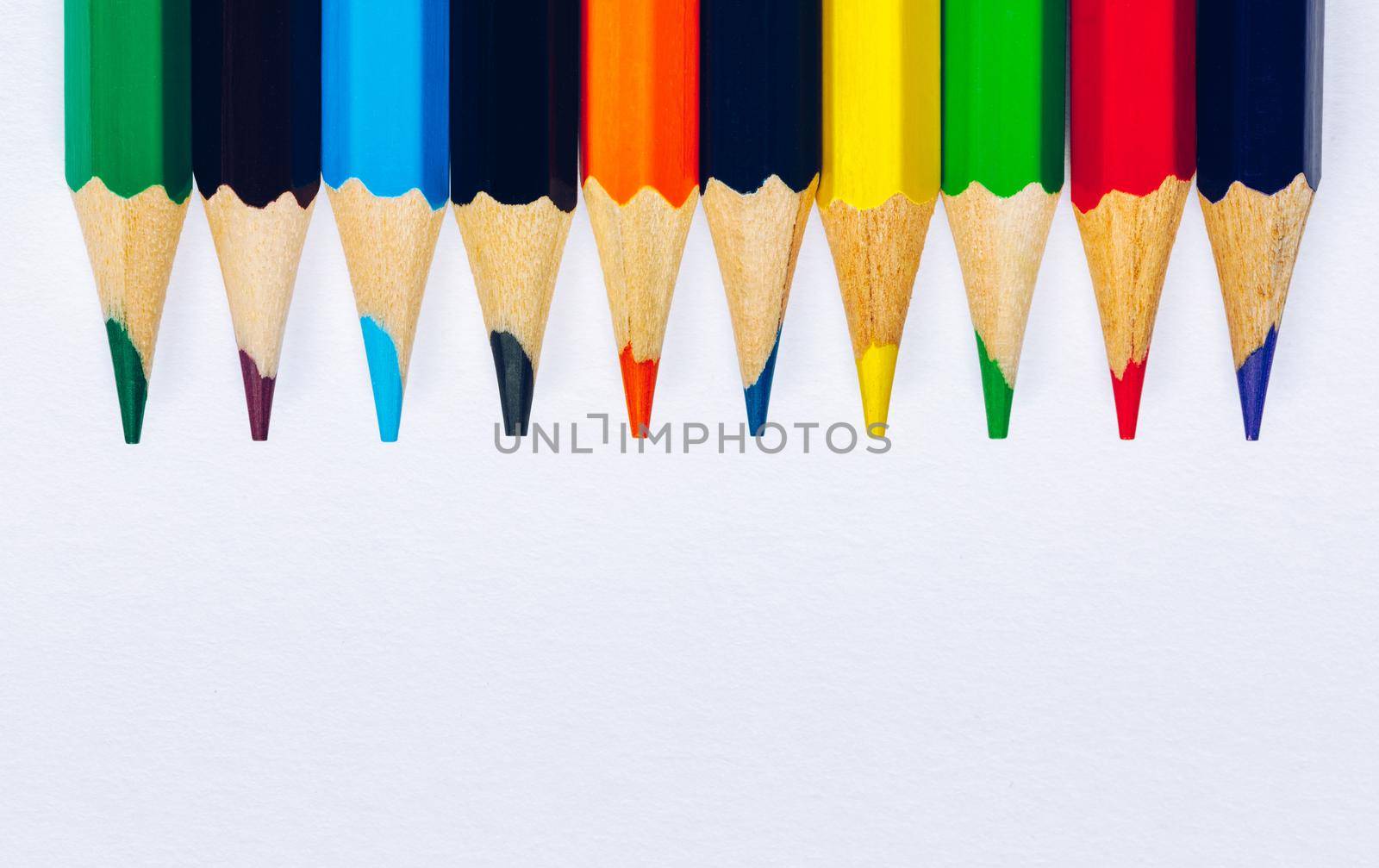 Color pencils isolated on white background. Close up of colored rainbow pencils for drawing, concept of preparing for school and discounts on stationery before the school year.