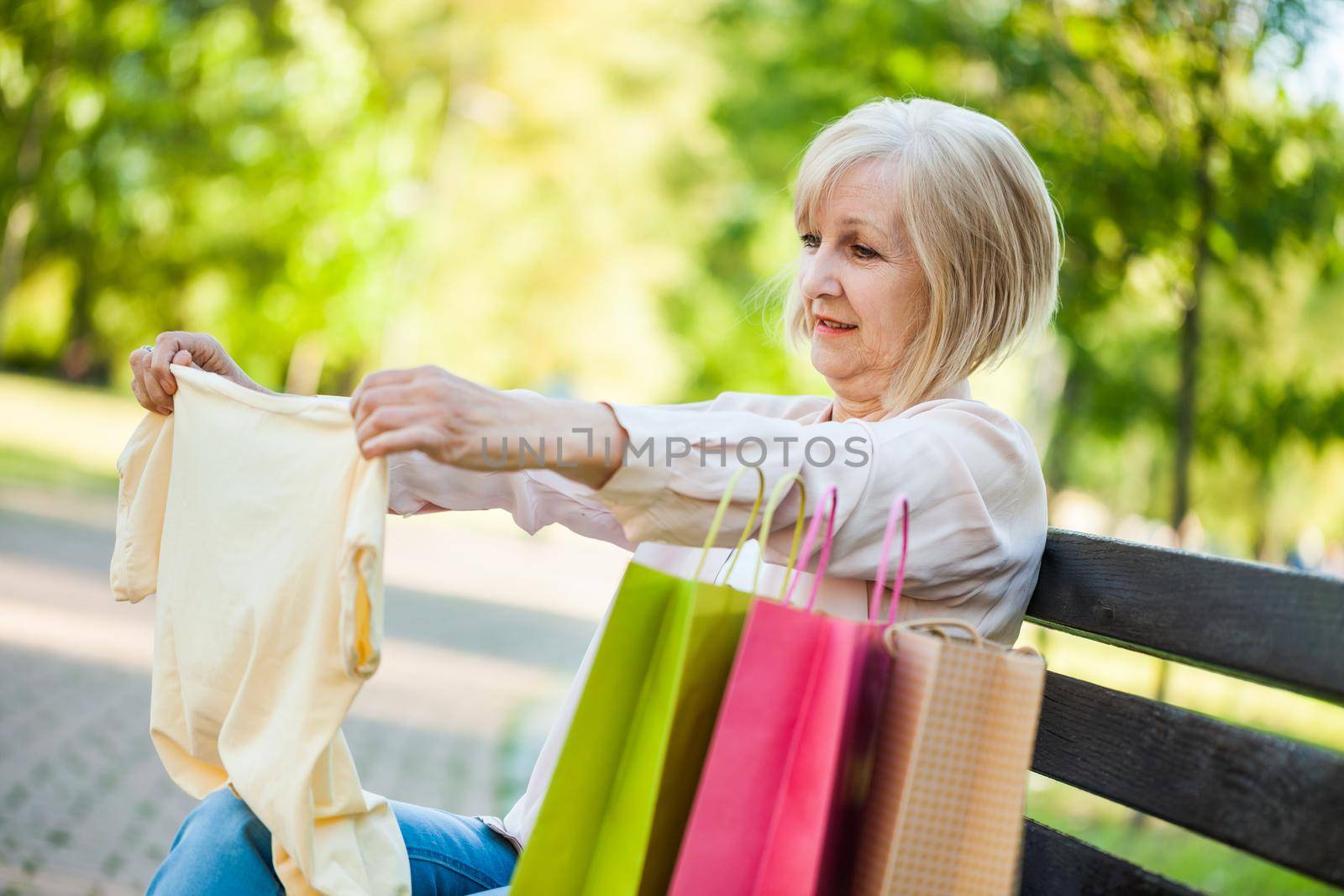 Happy adult woman sitting in park after shopping.