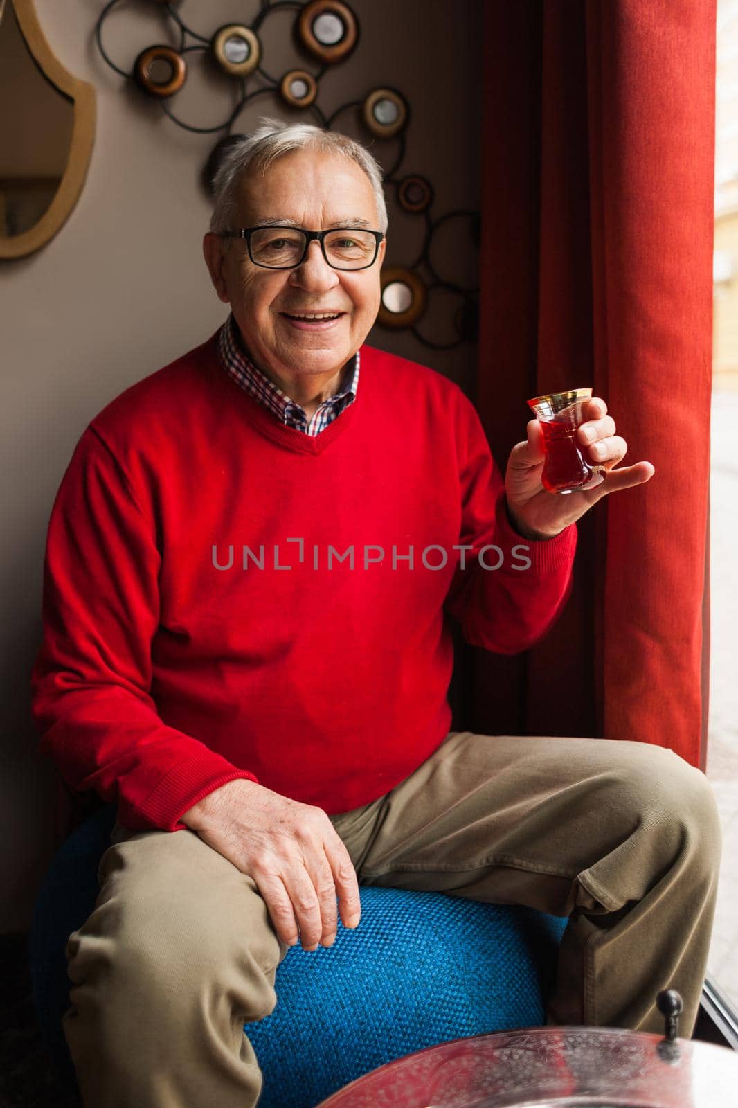 Senior man is drinking tea in a cafe.