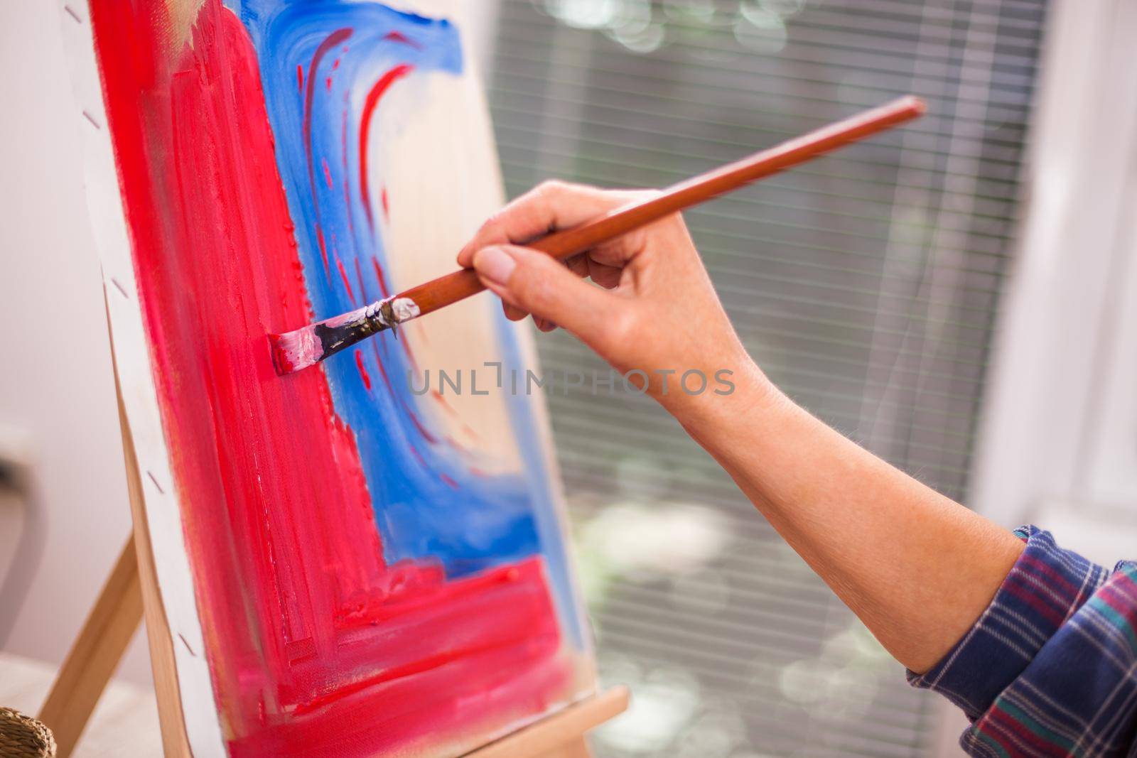 Close up of elderly woman's hand painting in her home.