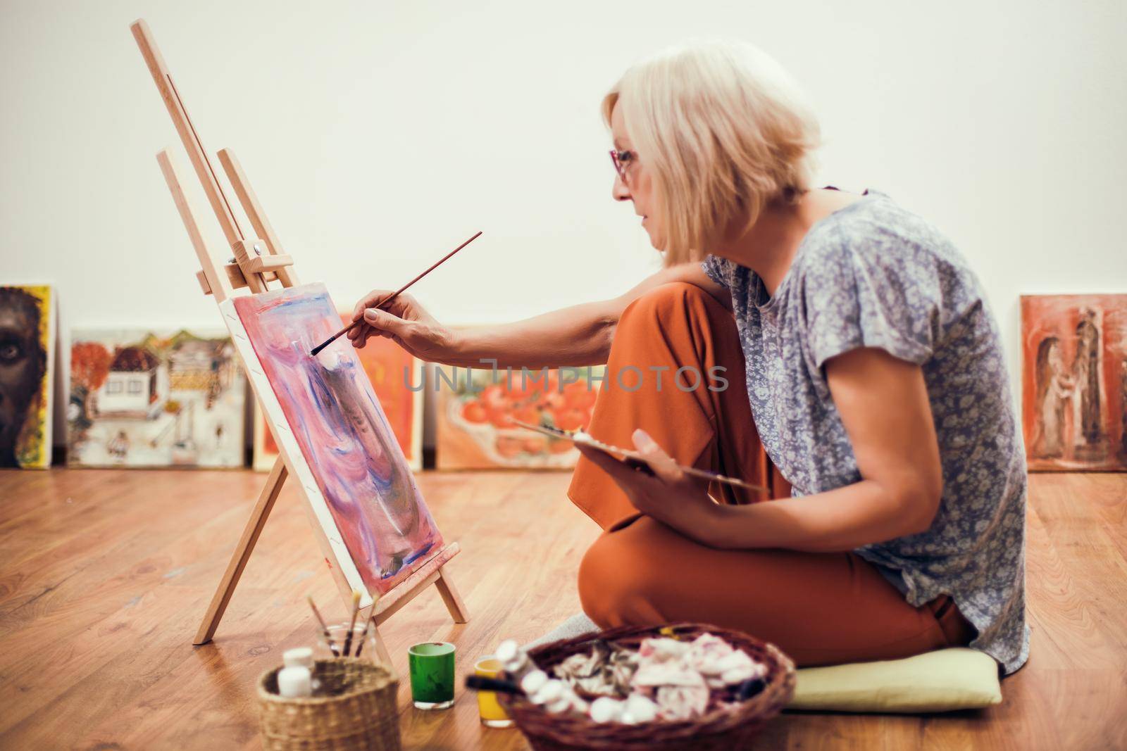 Elderly woman is painting in her home. Retirement hobby.