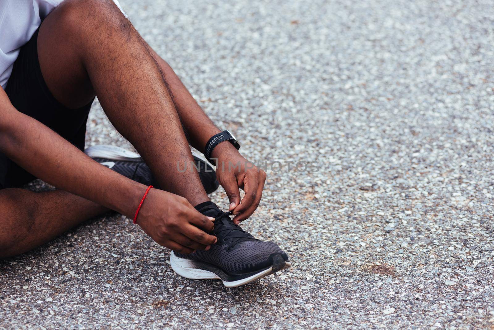 runner black man sitting shoelace trying running shoes by Sorapop