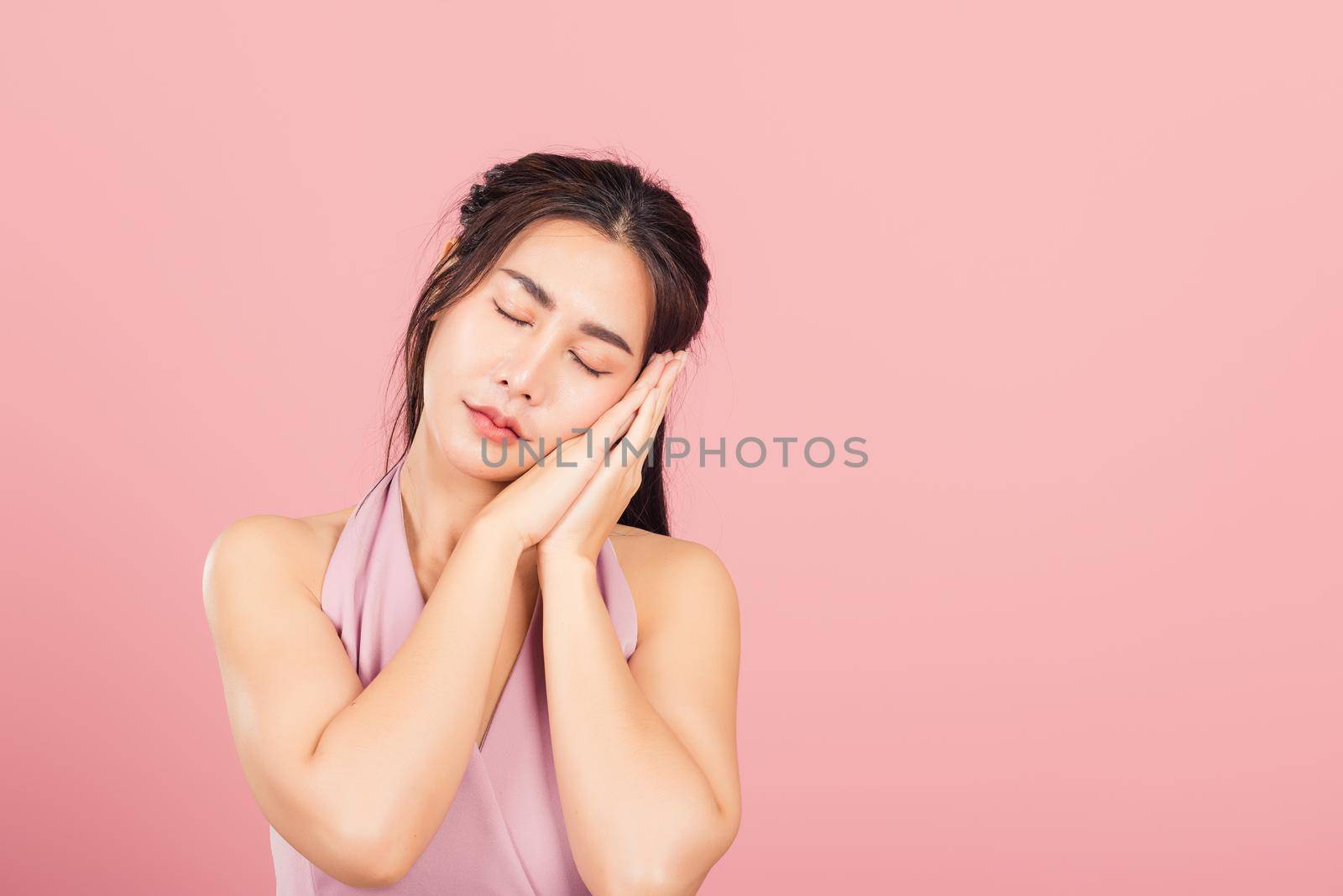 woman pretended emotions sleeping tired eyes closed dreaming with hands together near face by Sorapop