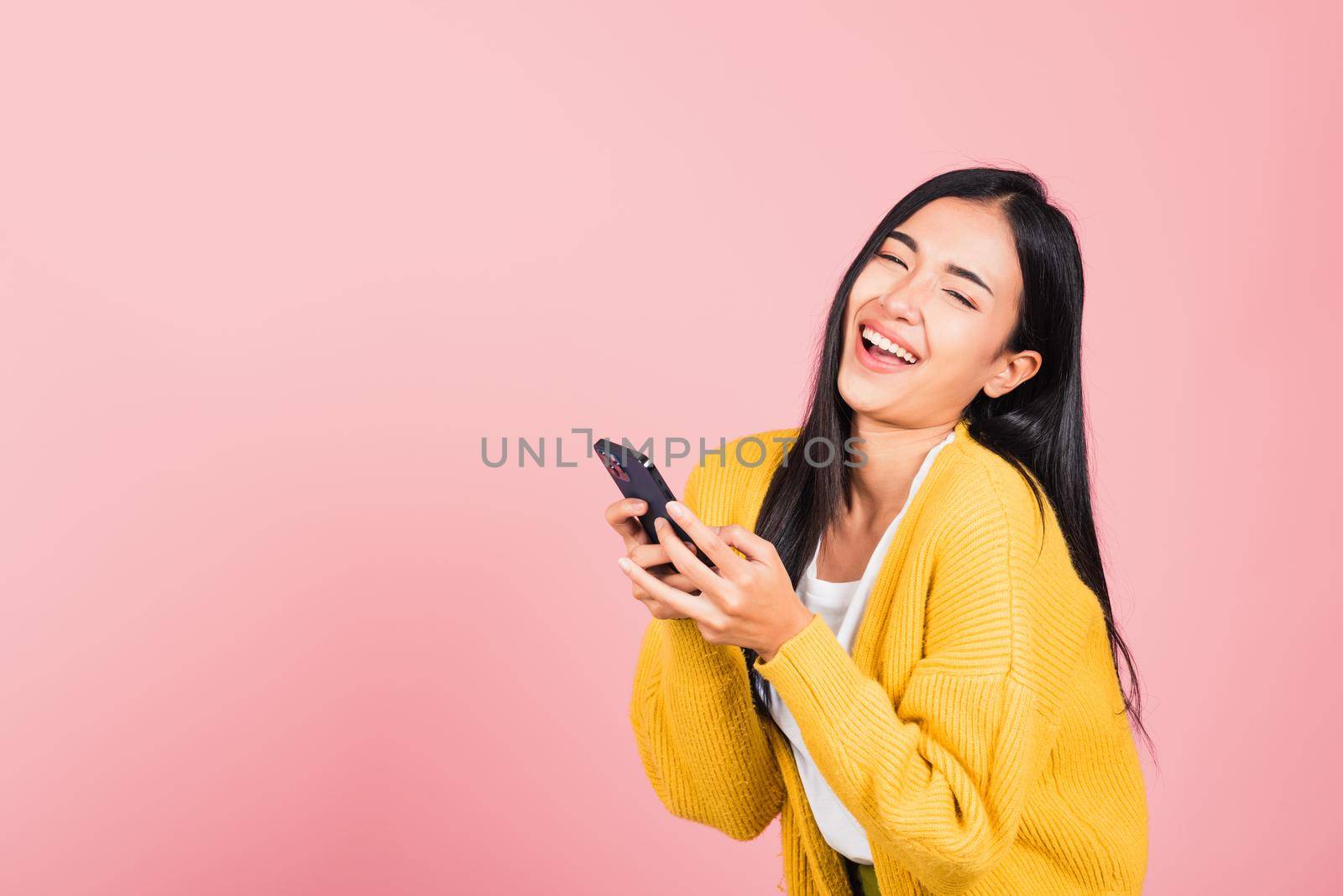 young woman excited laughing holding mobile phone by Sorapop