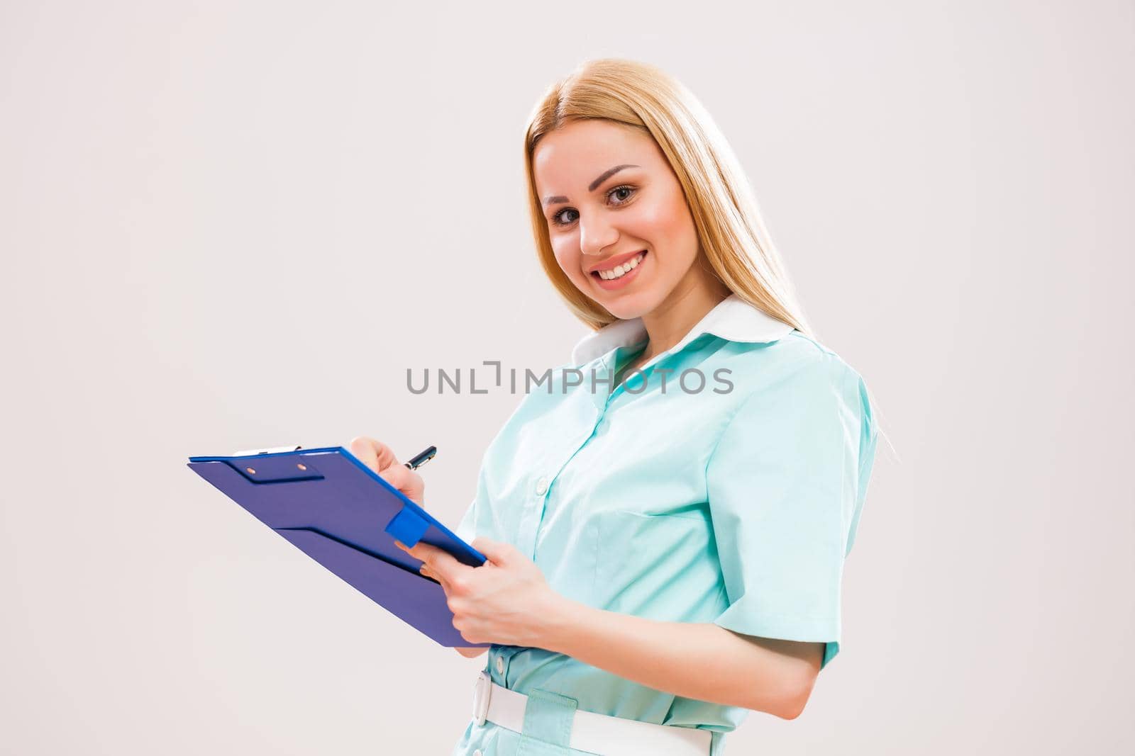 Portrait of young doctor who is holding clipboard and showing document with pen.