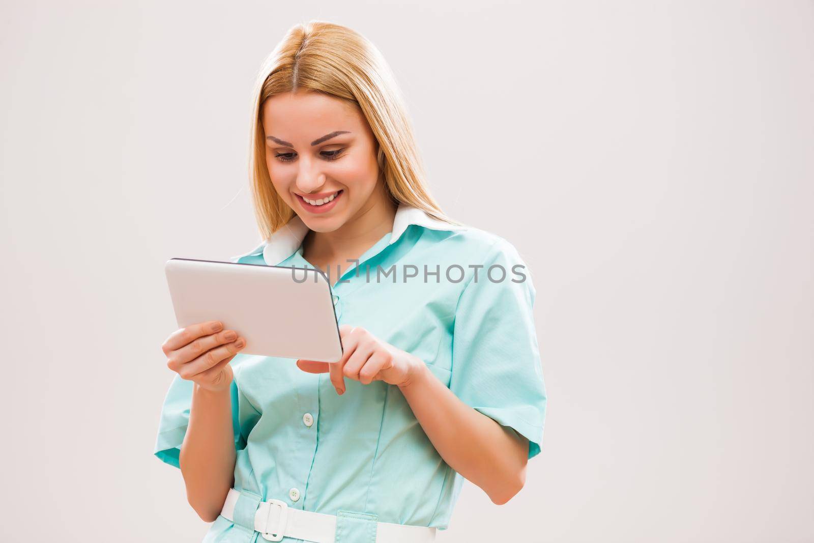 Portrait of young nurse who is examining therapies on digital tablet.